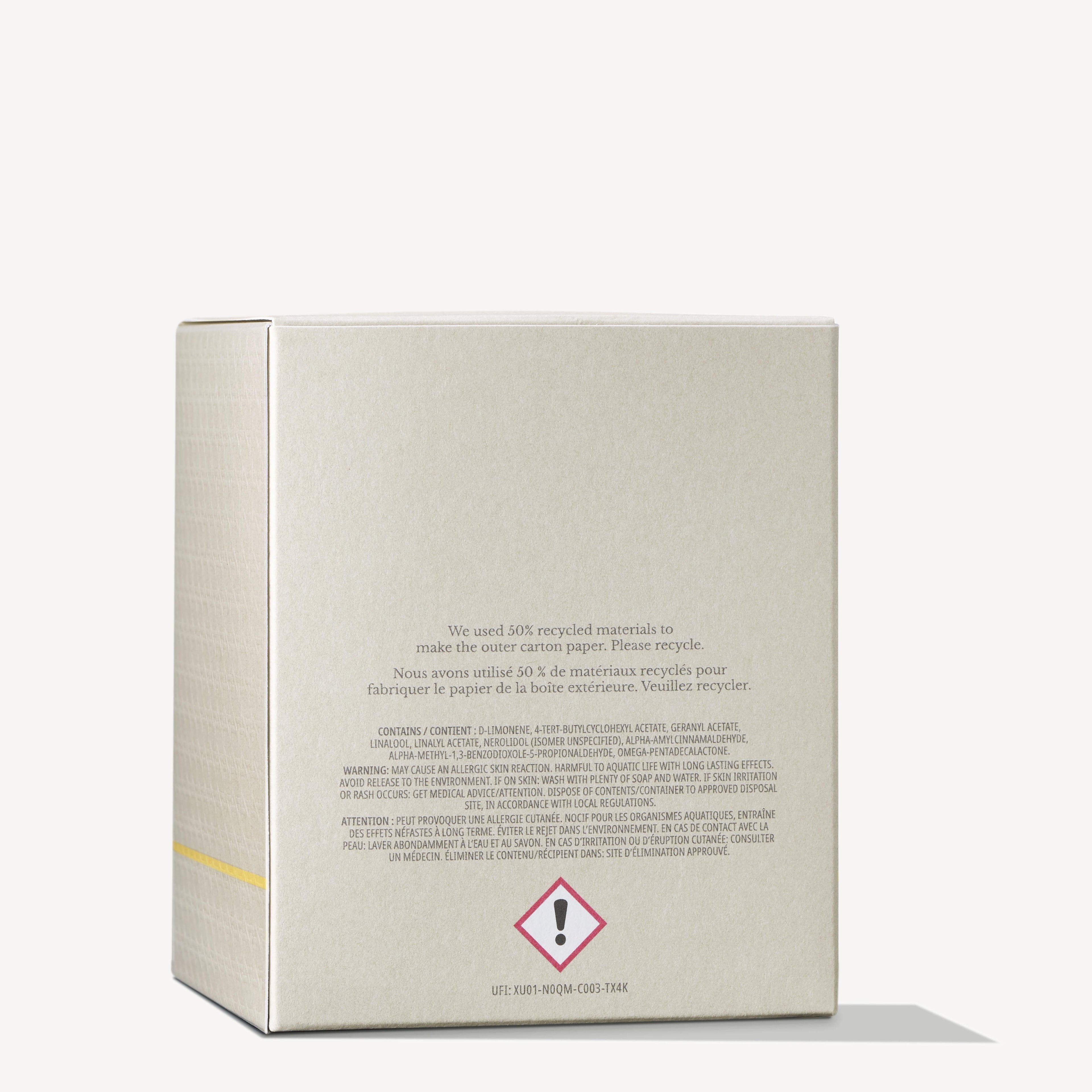 The image features a beige cardboard box displaying text and warning symbols on the back. It indicates that the packaging for the MoltonBrown Cyprus Orange & Bergamot Signature Candle 190g, which includes a single wick candle, is made from 50% recycled materials and is recyclable. A caution symbol is noticeable at the bottom.
