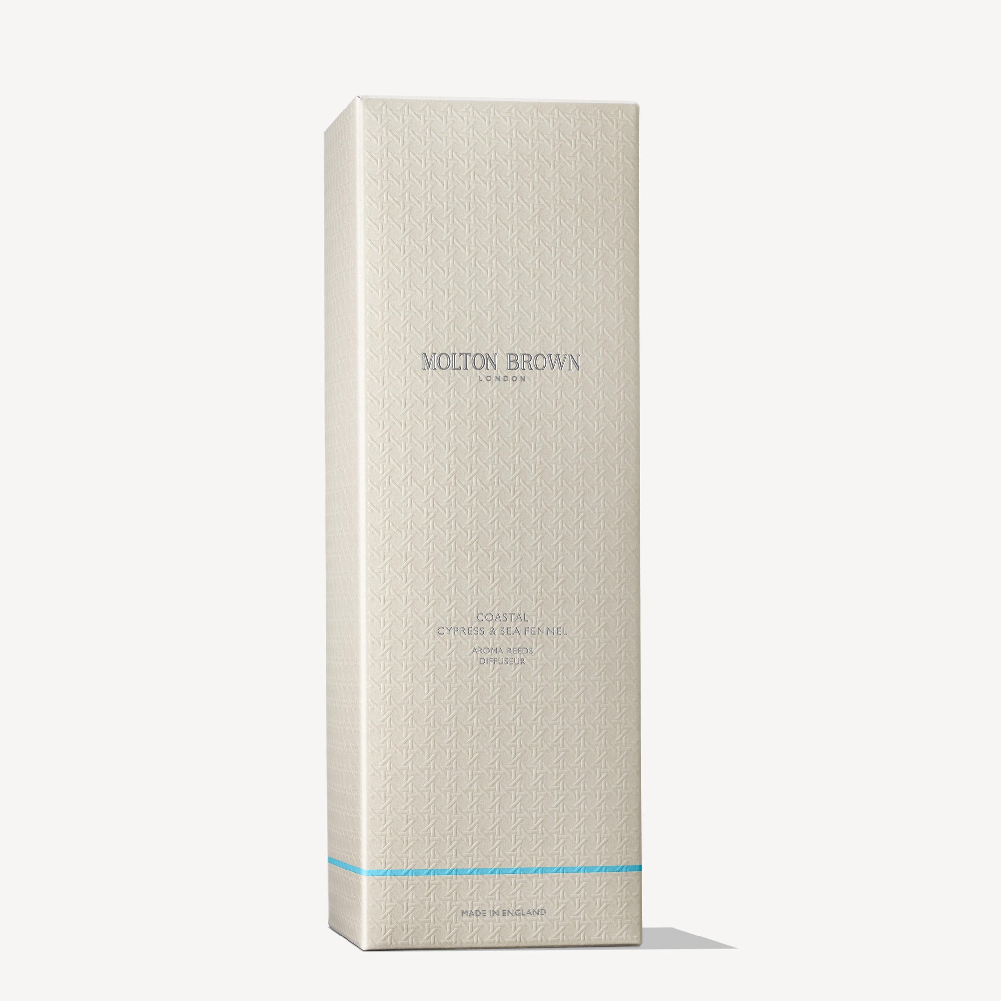 A tall, beige MoltonBrown Cyprus box with blue accents and embossed geometric patterns. The silver text reads Coastal Cypress & Sea Fennel Aroma Reeds 150ml, featuring an aromatic fragrance reminiscent of a sea breeze scent.
