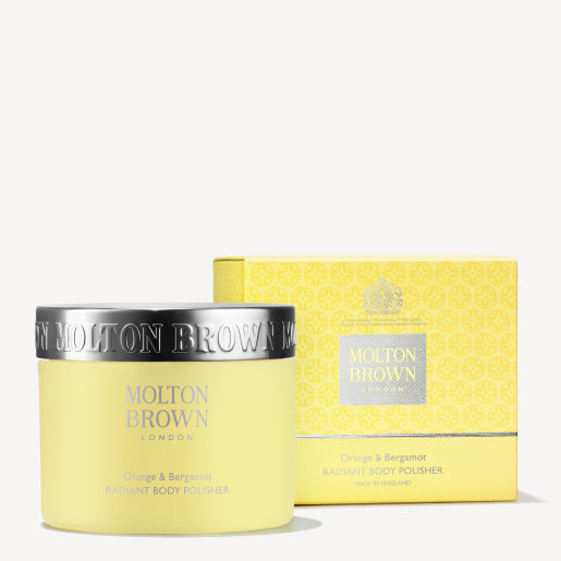 A jar of MoltonBrown Cyprus Orange & Bergamot Radiant Body Polisher, a yellow exfoliating body scrub, sits before its matching box. Both exude delightful citrus notes with orange and bergamot scents, complemented by elegant text and design on the packaging.