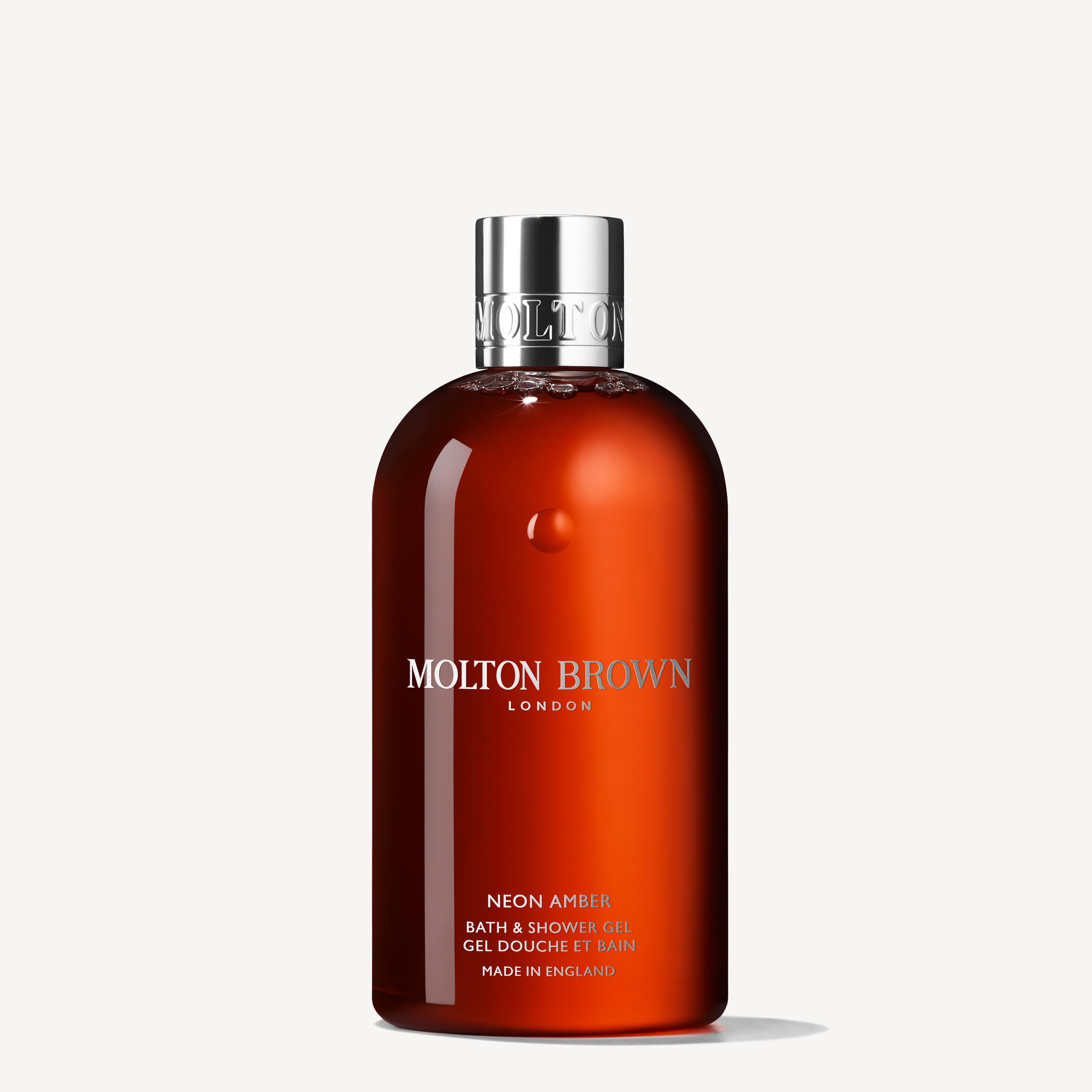 A bottle of Neon Amber Bath & Shower Gel 300ml, infused with refreshing Mandarin Oil, comes in a rich amber container accented by a sleek silver cap. The MoltonBrown Cyprus product prominently displays "Neon Amber" and includes brand details alongside a declaration of its English origin.