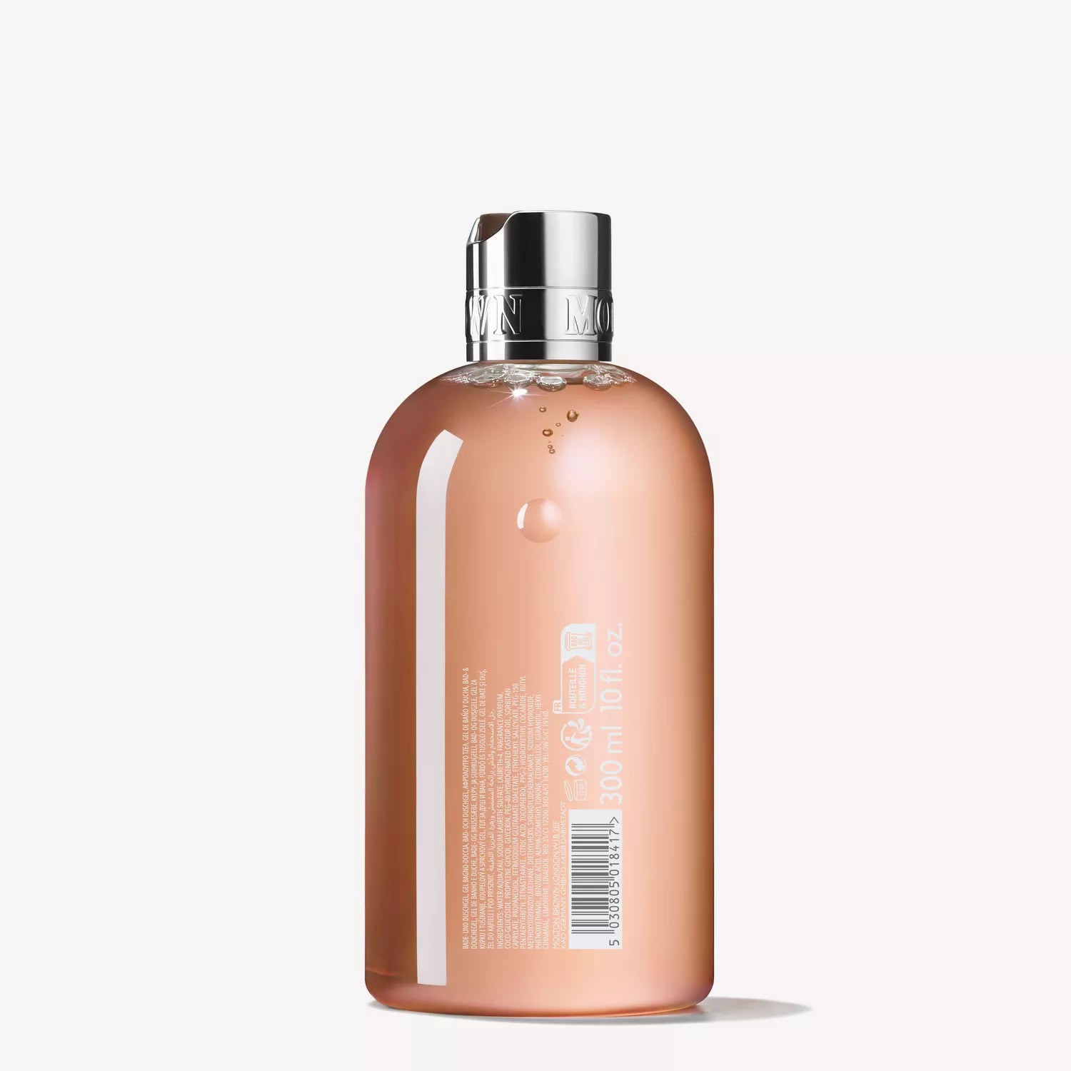 A transparent bottle with a shiny silver cap contains a pink liquid, reminiscent of an English orchard. This bottle, likely holding the floral-fruity Gift Product 1 bath & shower gel from MoltonBrown Cyprus, features a barcode and text detailing the product.
