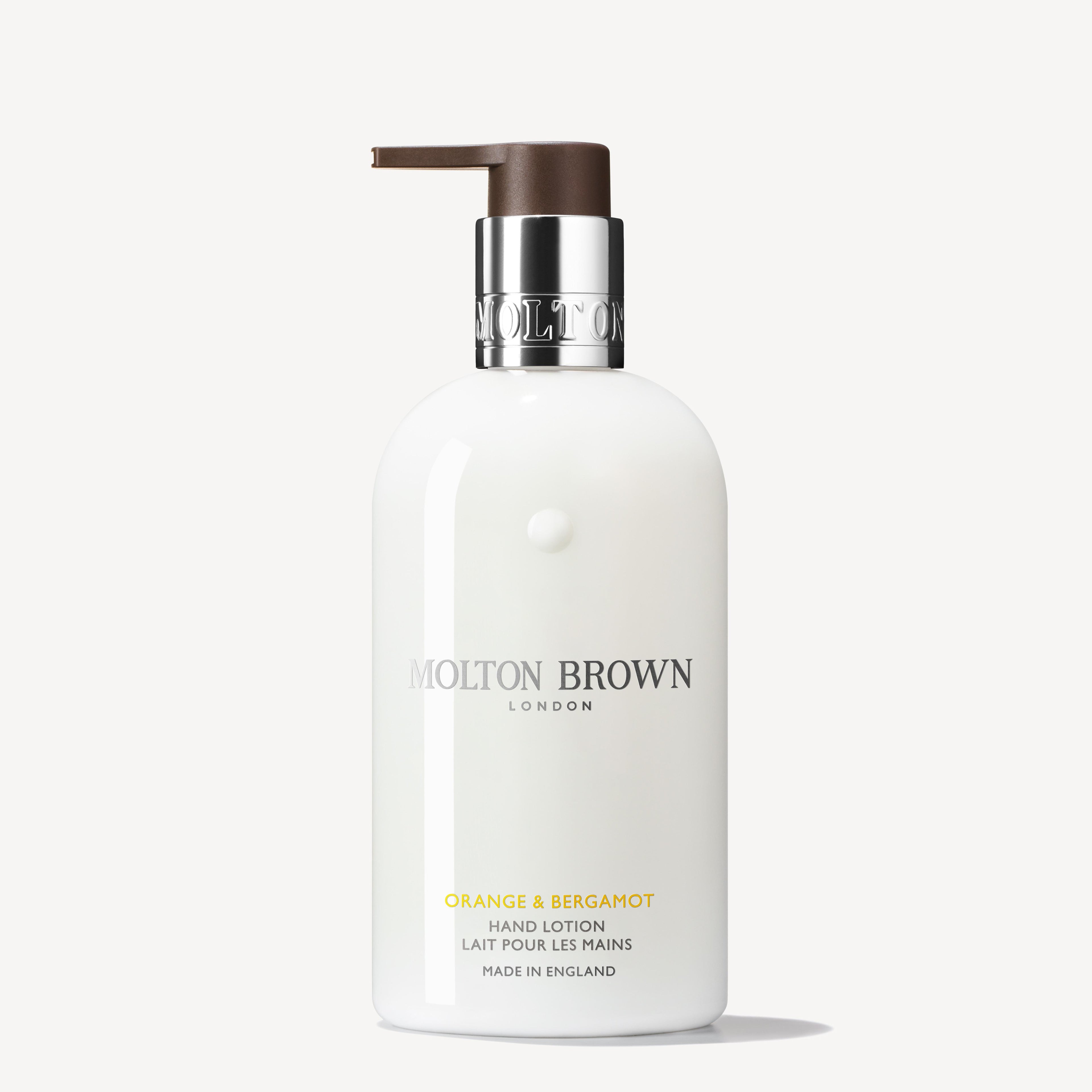 A 300ml bottle of MoltonBrown Cyprus Orange & Bergamot Hand Lotion, infused with the essence of neroli, showcases a brown pump and silver collar with the brand's logo. The label prominently features "London" and "Made in England," set against a crisp white backdrop.