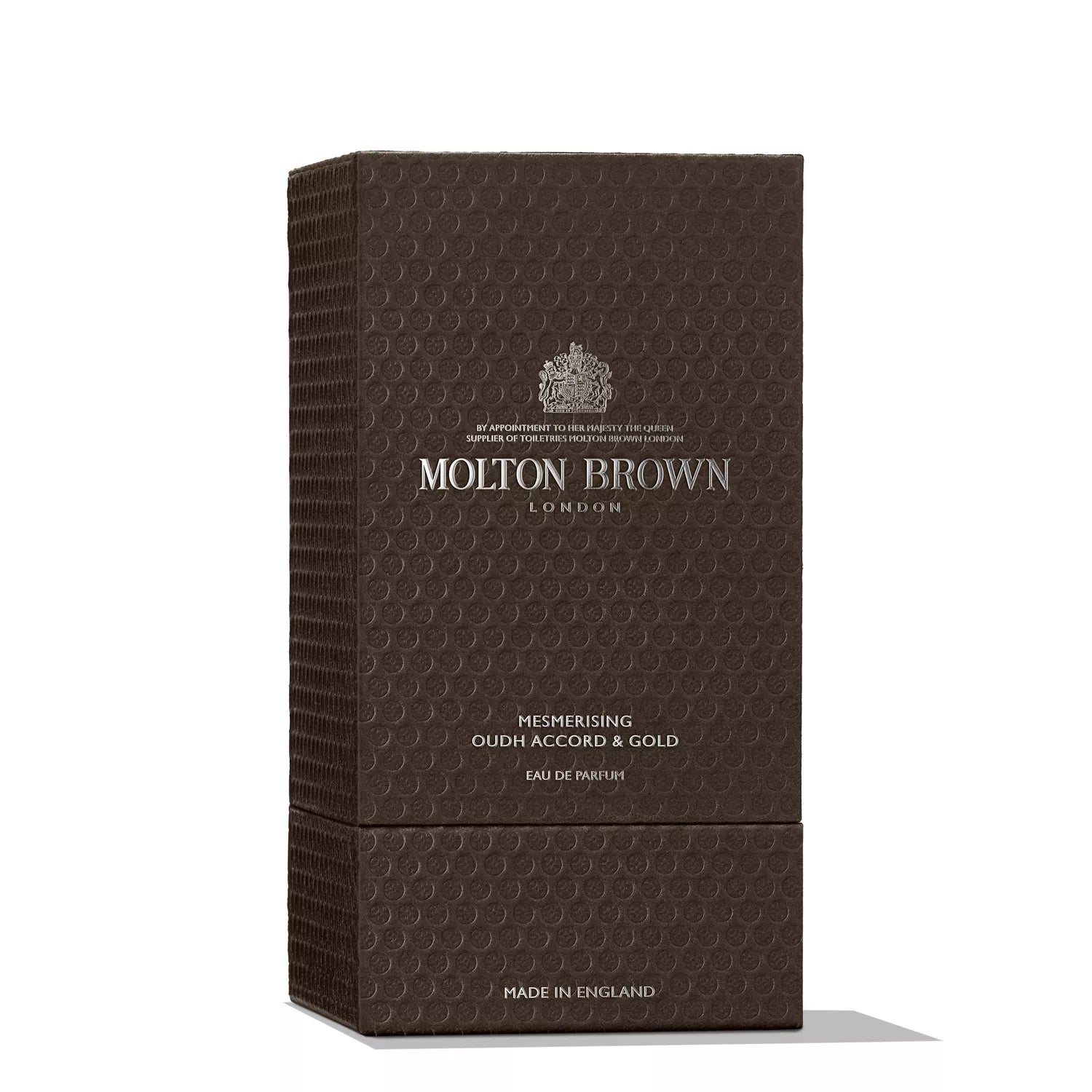 A textured dark brown box of MoltonBrown Cyprus Mesmerising Oudh Accord & Gold Eau de Parfum 100ml, with silver embossed text and crest, holds a collectible glass bottle of this saffron oud fragrance. Made in England appears at the bottom.