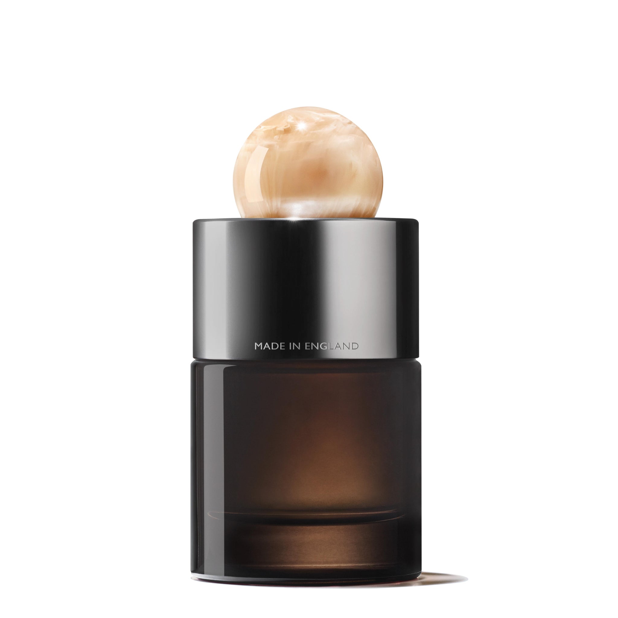 The Jasmine & Sun Rose Eau de Parfum 100ml from MoltonBrown Cyprus boasts a sleek black base and a spherical, marble-like beige cap that exudes elegance. "Made in England" is inscribed on the silver band just below the cap, adding to its sophistication. Its modern design perfectly complements the rich jasmine notes of this refined fragrance.