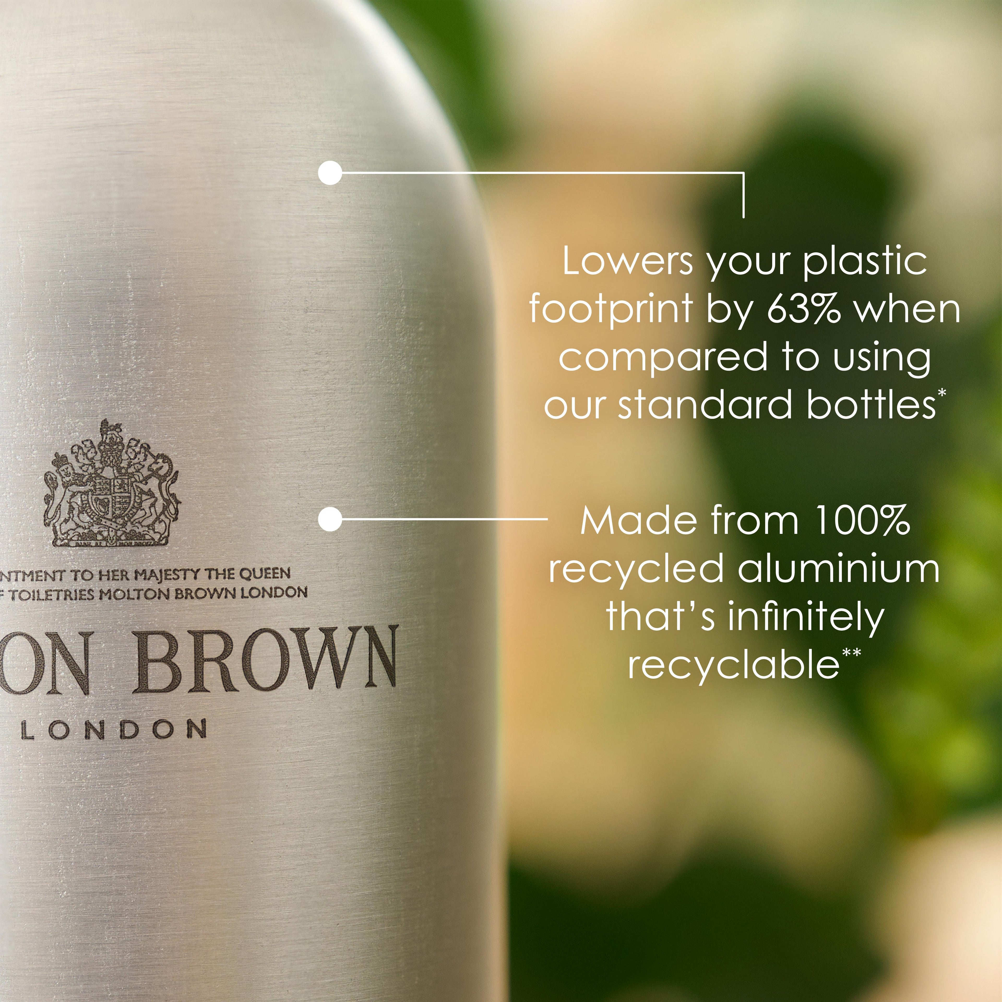 A silver bottle from MoltonBrown Cyprus, the Re-charge Black Pepper Infinite Bottle 400ml, emphasizes its eco-friendly qualities with a 63% reduction in plastic footprint and construction from recycled aluminum. Set against vibrant green foliage, this woody-citrus body wash delivers sustainability without compromise.