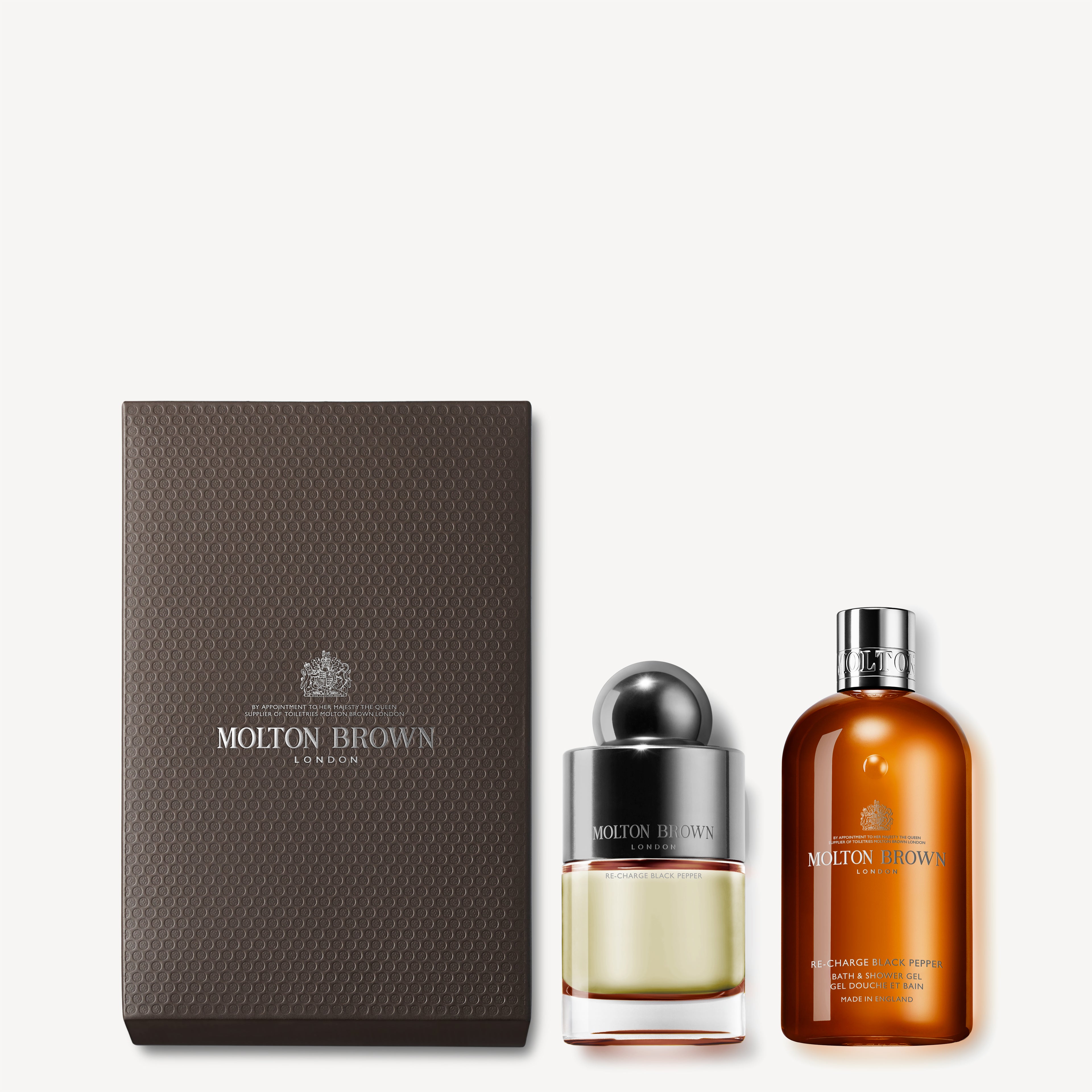 Introducing the MoltonBrown Cyprus 100ml Re-charge Black Pepper Fragrance Gift Set, featuring a sophisticated brown textured box, a clear Eau de Toilette bottle with a shiny cap, and an appealing black pepper scented duo in a brown bottle with an orange label.