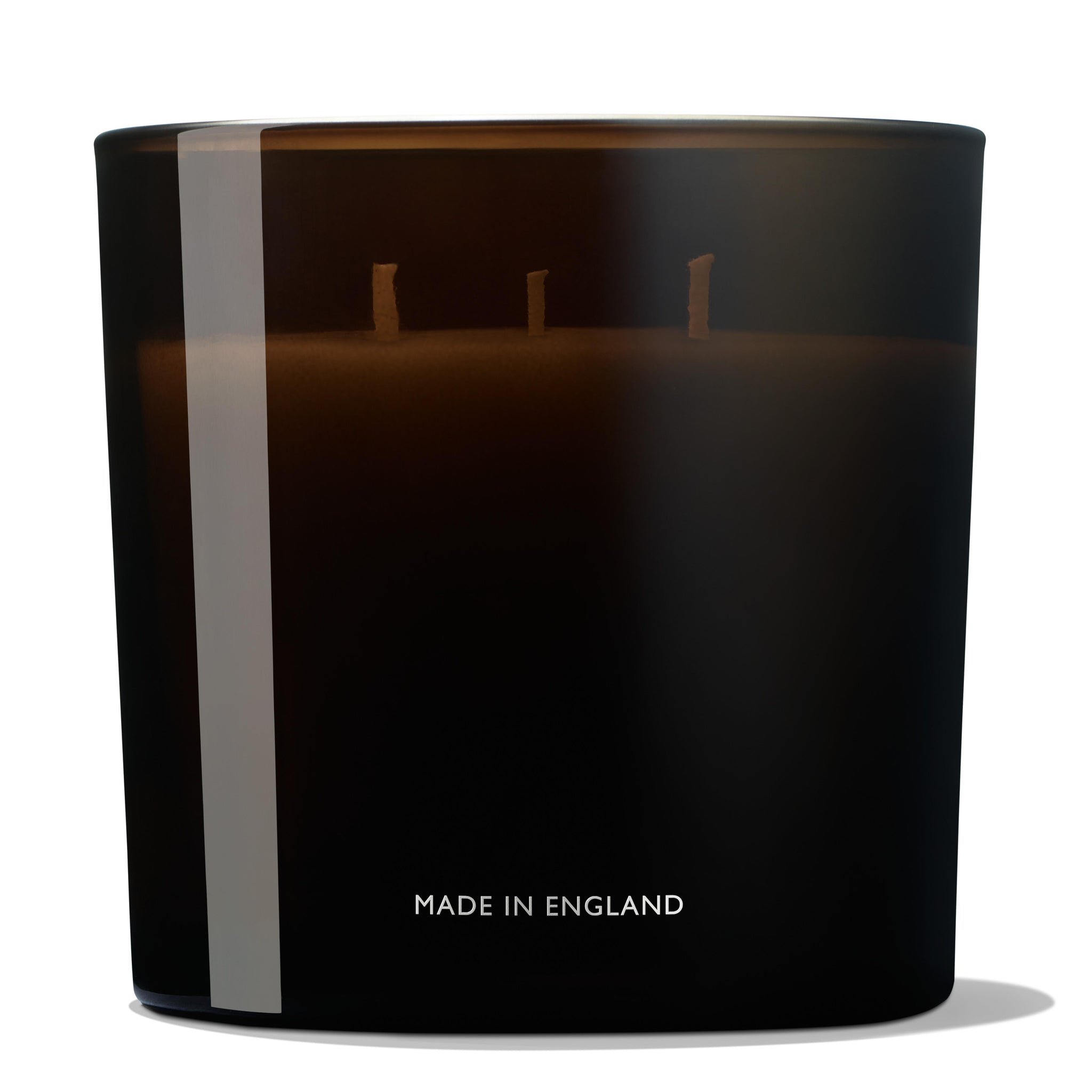 The Re-charge Black Pepper Luxury Candle 600g by MoltonBrown Cyprus is a sleek, dark cylindrical candle holder crafted from recycled materials, featuring three unlit wicks. Near the base, "MADE IN ENGLAND" is elegantly printed. A vertical reflective stripe enhances its minimalist and contemporary design, making it a stylish addition to modern spaces.