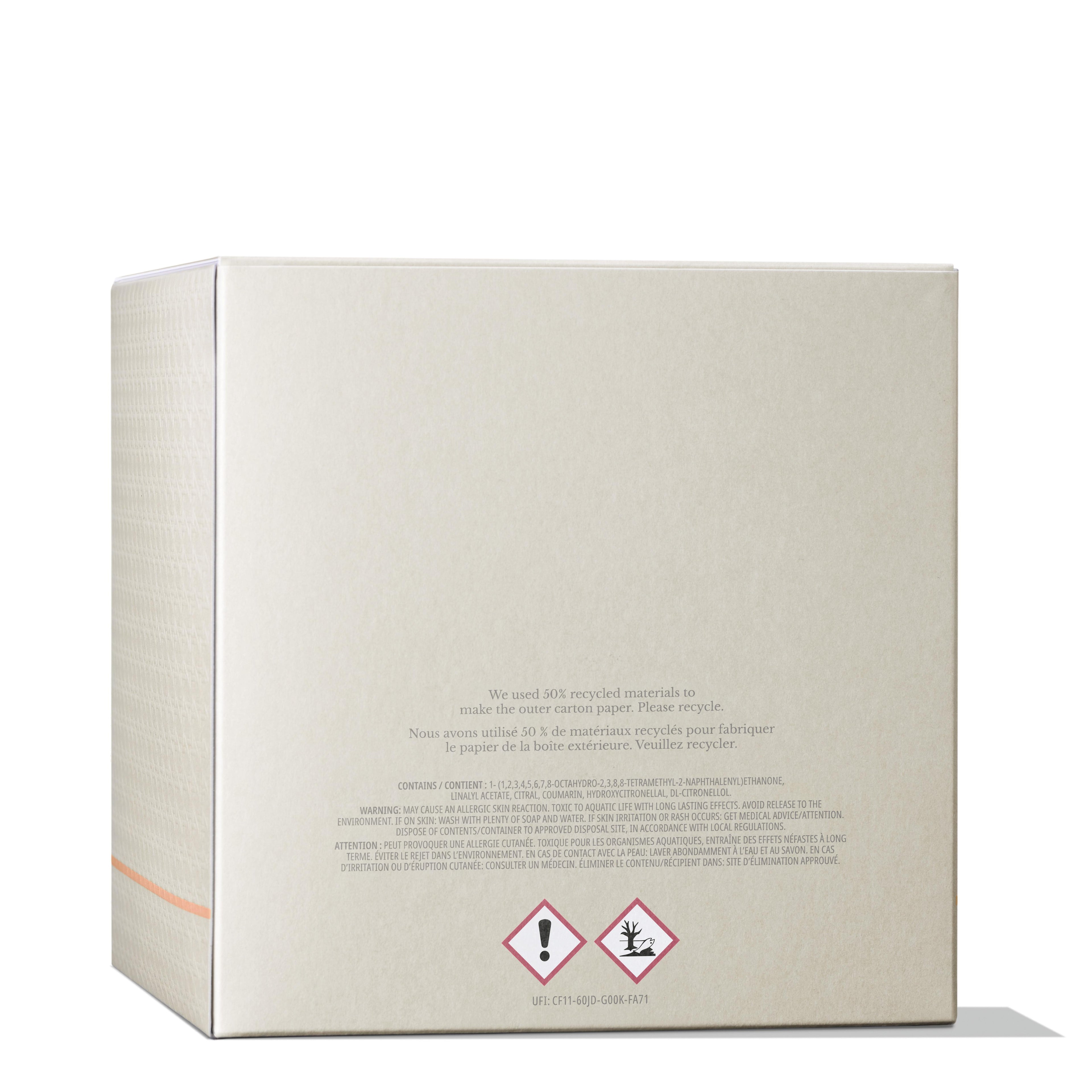 The Re-charge Black Pepper Luxury Candle 600g by MoltonBrown Cyprus is packaged in a beige box with a subtle texture. It prominently features a message highlighting its use of 30% recycled materials and Madagascan black pepper. The box also includes hazard symbols for irritants and aquatic toxicity, and boasts a minimal design accentuated by an orange line on the side.