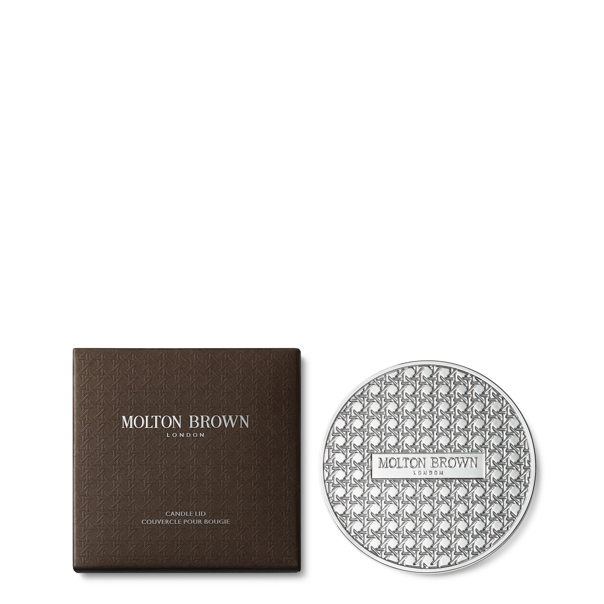 The Signature Candle Lid 98g by MoltonBrown Cyprus showcases a geometric pattern and the iconic logo with chrome plating. It is accompanied by a dark brown box featuring white text that reads "MoltonBrown Cyprus" and "Signature Candle Lid." This elegant, intricate design seamlessly enhances any collection of scented candles.