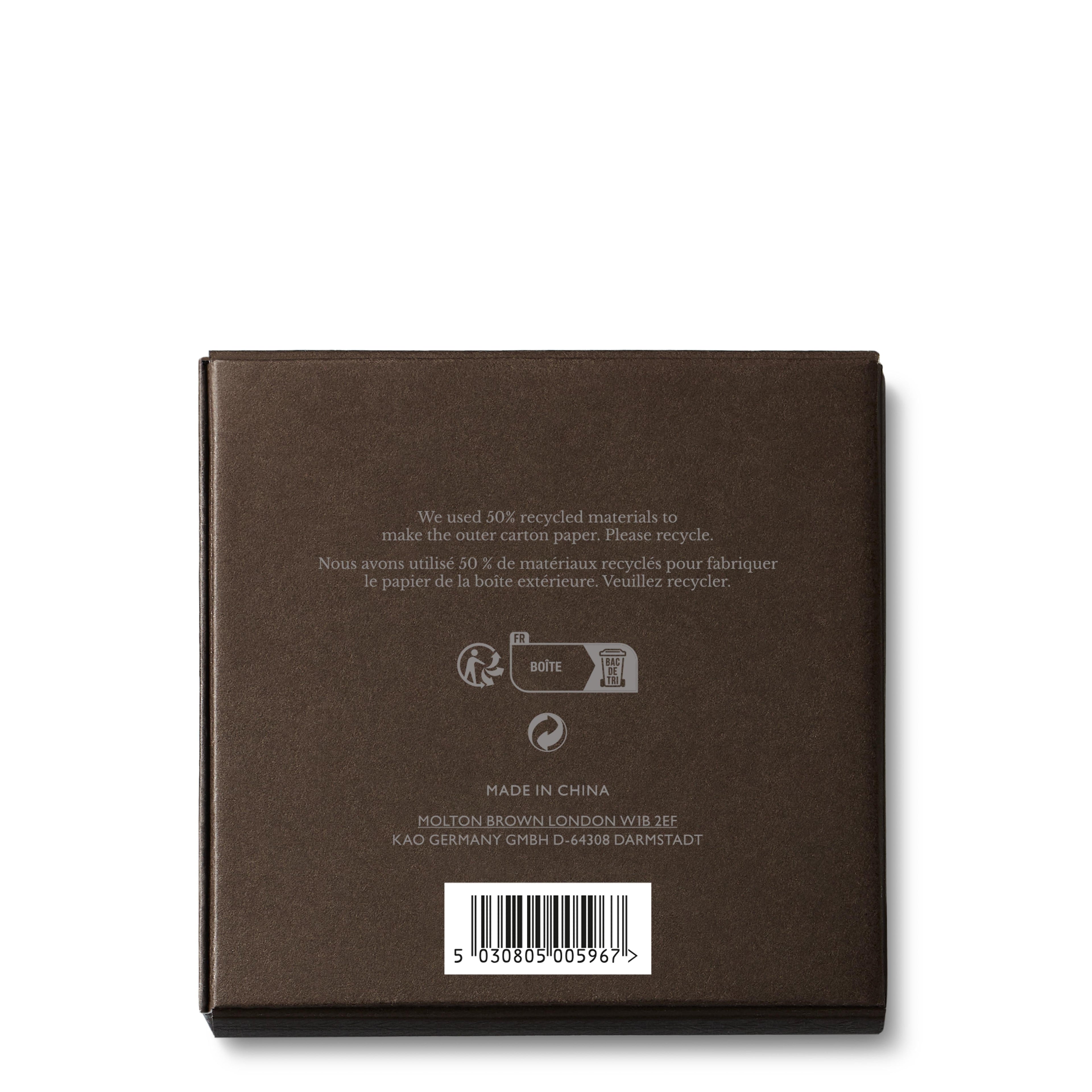 The image features the back of a brown box adorned with recycling symbols and bilingual text in English and French regarding the use of recycled materials. It states "Made in China" and displays a barcode at the bottom, suggesting that it contains MoltonBrown Cyprus Signature Candle Lid 98g, which may include elegantly scented candles with exquisitely designed lids.