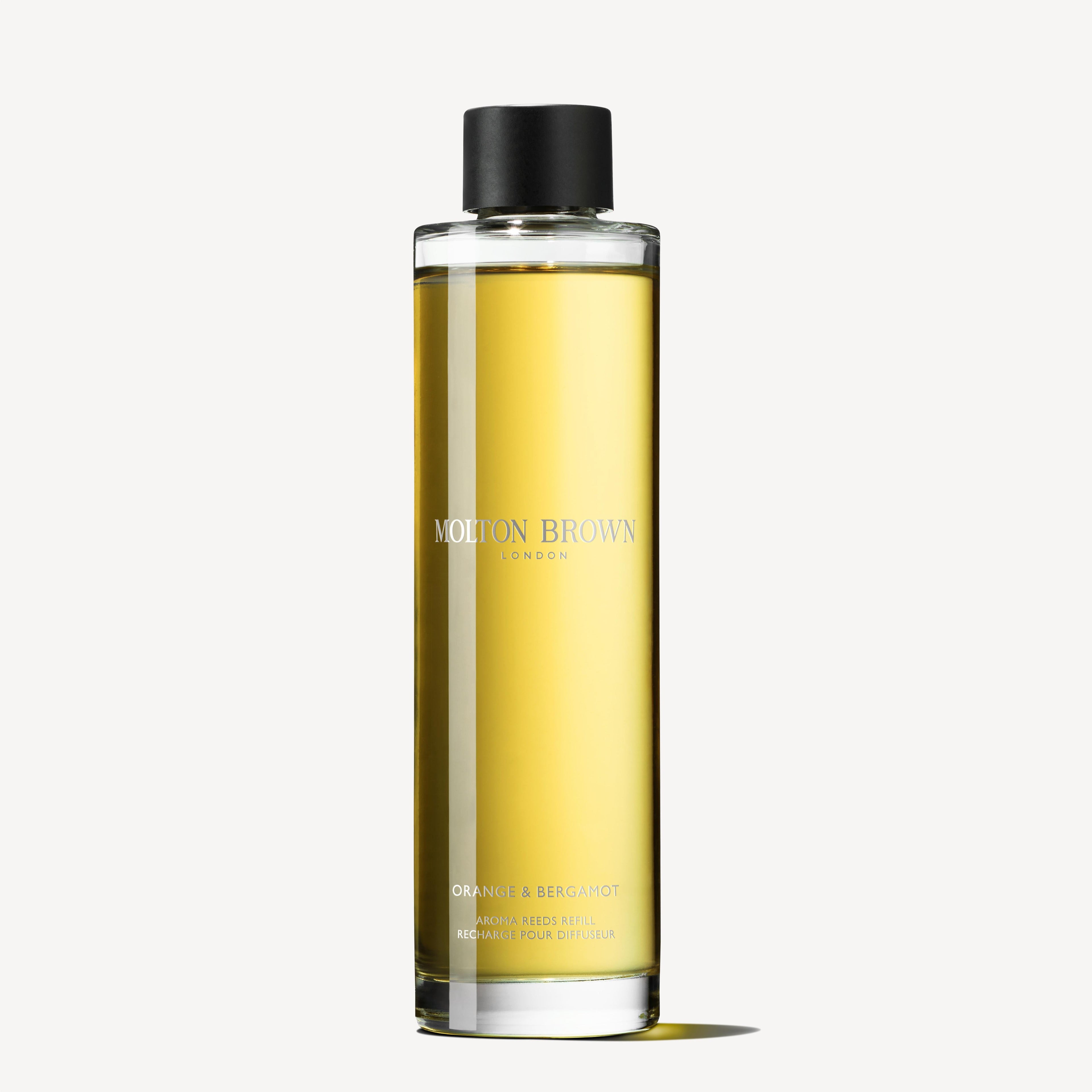 A tall, elegant bottle labeled MoltonBrown Cyprus, containing a yellow liquid and topped with a black cap, is showcased. The bottom label reads Orange & Bergamot Aroma Reeds Refill 150ml along with descriptive text. This citrus home fragrance stands out against the light gray background.