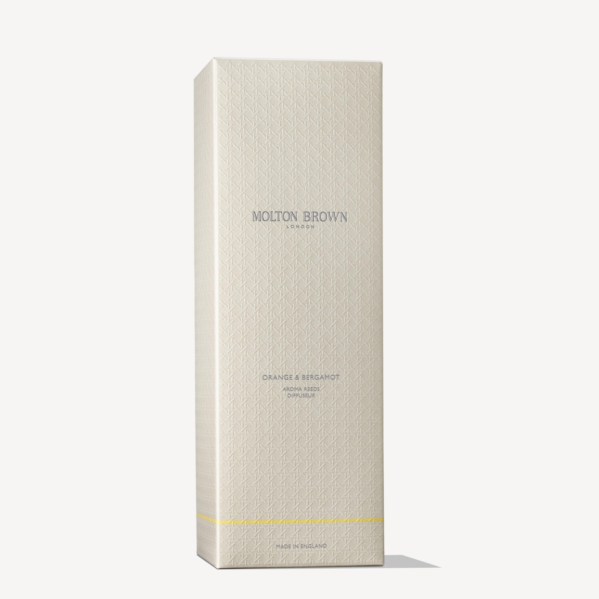 The Sevillian Orange reed diffuser, nestled inside a beige rectangular box with a delicate patterned texture, is branded as MoltonBrown Cyprus. The text "MoltonBrown Cyprus" is prominently centered near the top of the packaging, followed by "Orange & Bergamot Aroma Reeds 150ml." A yellow stripe at the bottom suggests the lively scent of neroli contained within.