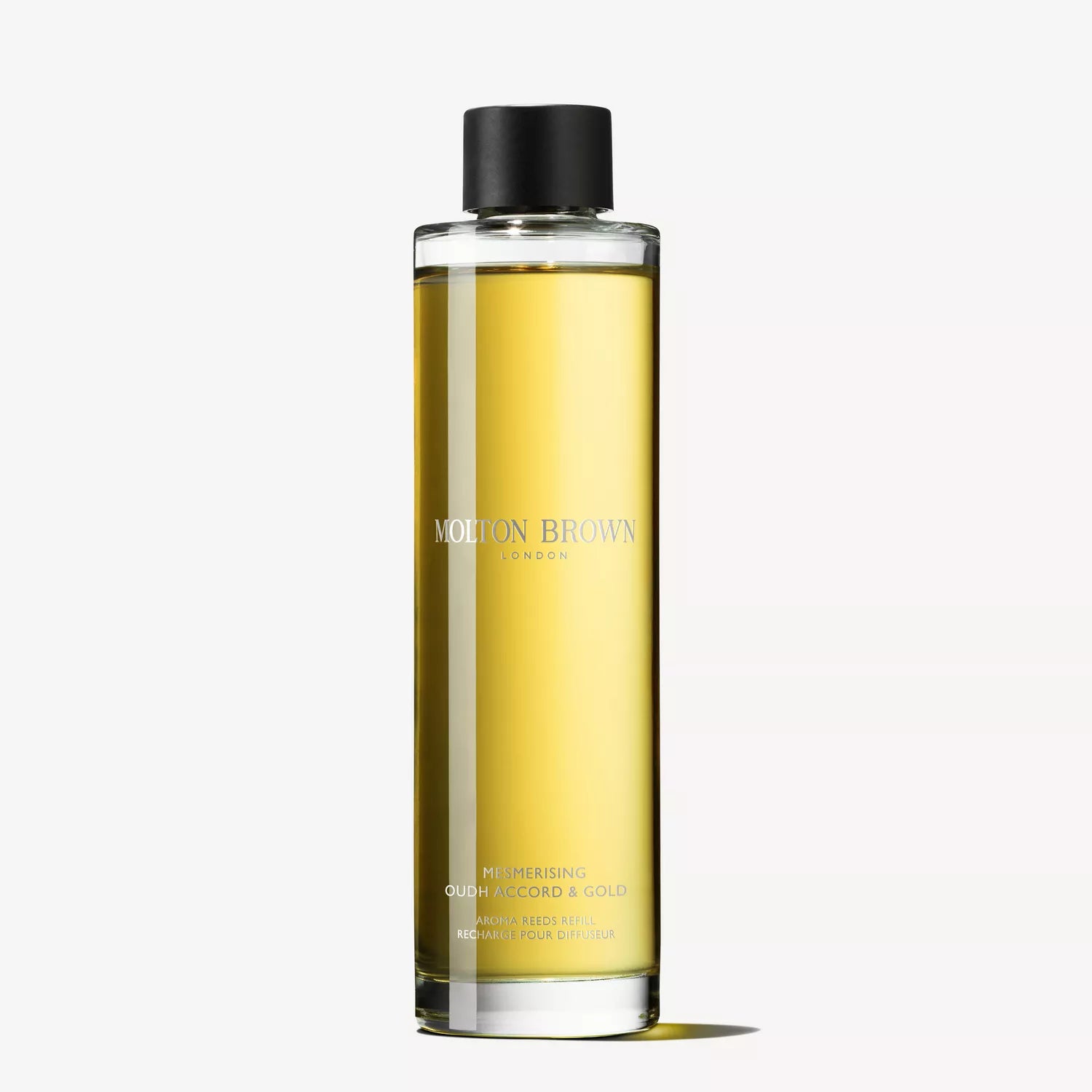 A tall, clear bottle with yellow liquid and a black cap, labeled MoltonBrown Cyprus. The Mesmerising Oudh Accord & Gold Aroma Reeds Refill 150ml offers a luxurious fragrance for any room.