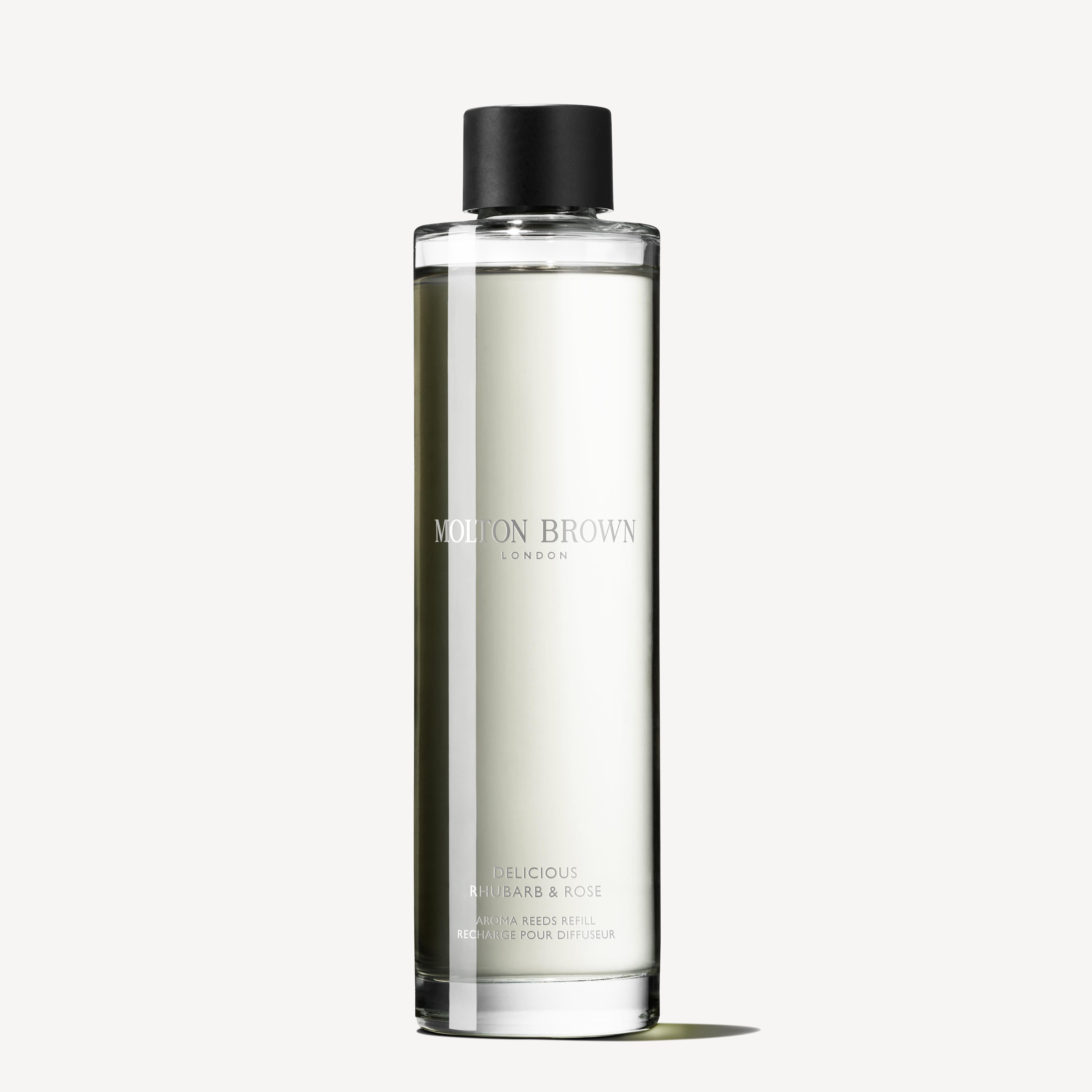 A clear cylindrical bottle with a black cap, labeled Molton Brown Cyprus and Delicious Rhubarb & Rose Aroma Reeds Refill 150ml, subtly infused with hints of vanilla. The bottle contains a liquid that casts a gentle shadow against a plain background.