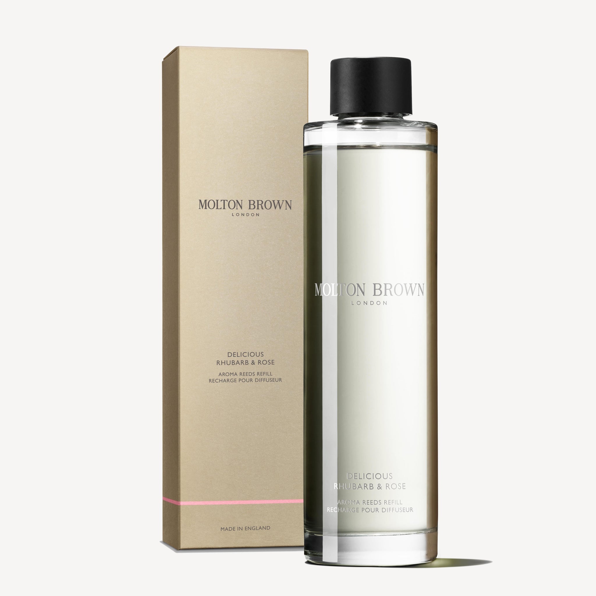 A clear bottle of MoltonBrown Cyprus Delicious Rhubarb & Rose Aroma Reeds Refill 150ml, carrying the subtle scent of grapefruit, is displayed alongside its matching rectangular box adorned with pink accents and a minimalistic label.