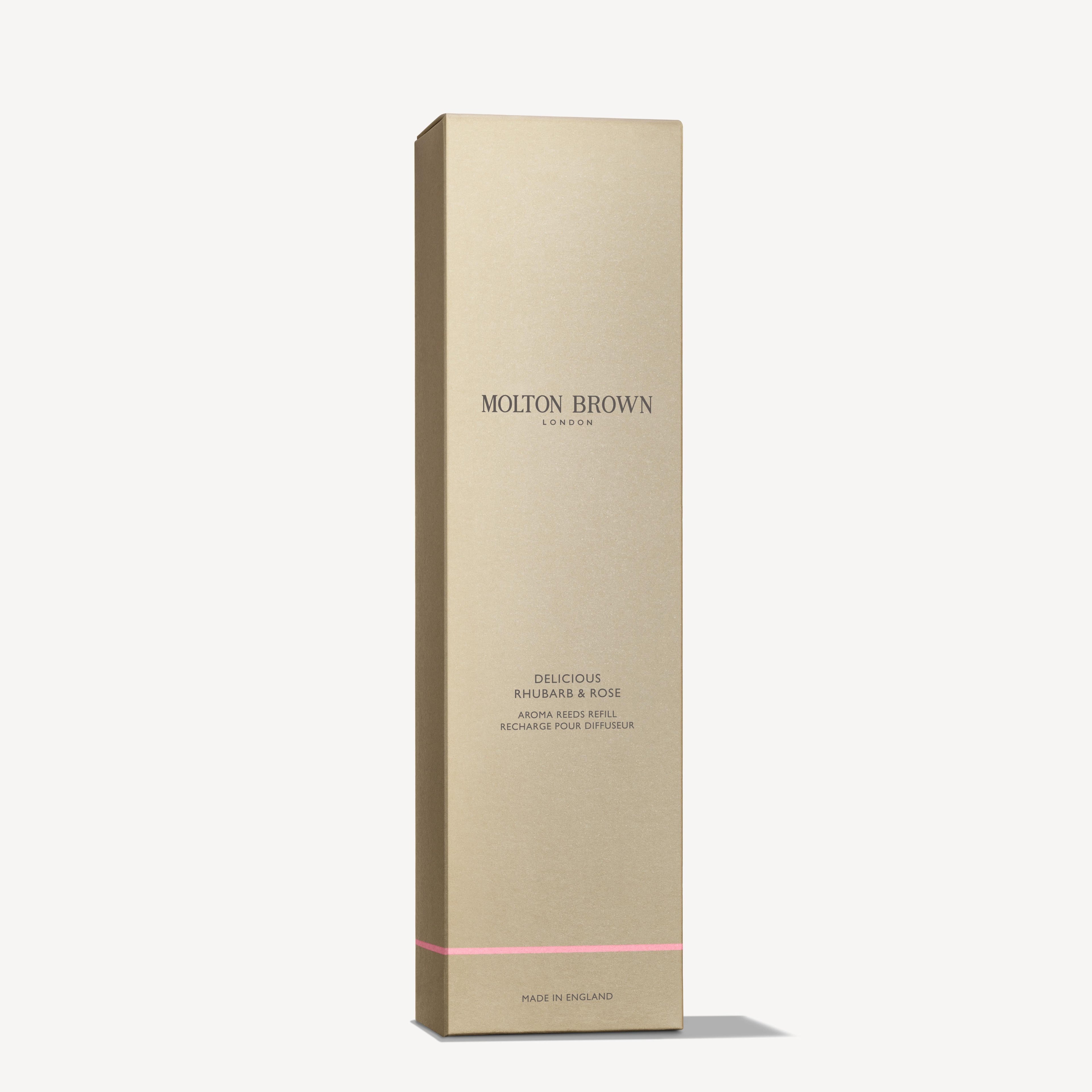 A slim, rectangular gold box featuring MoltonBrown Cyprus prominently in the center. Below, it states Delicious Rhubarb & Rose Aroma Reeds Refill 150ml. A delicate touch of grapefruit essence complements the pale pink line accent at the bottom. The box is positioned upright against a light background.