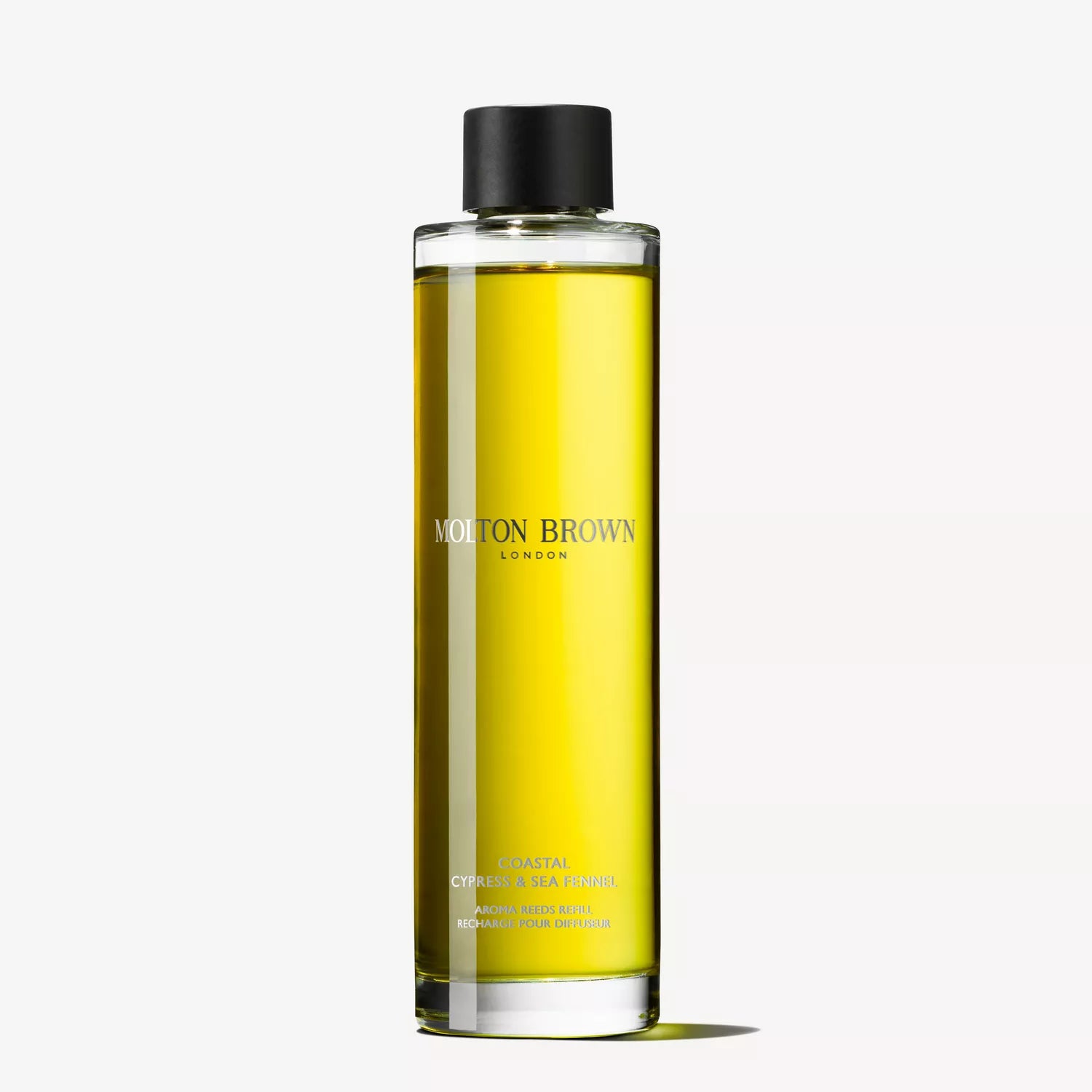 A tall, cylindrical bottle of Molton Brown Cyprus Coastal Cypress & Sea Fennel bath and shower gel with marine notes. The clear bottle reveals yellow liquid, topped with a black cap. The label displays the brand name, echoing the design of their Coastal Cypress & Sea Fennel Aroma Reeds collection.