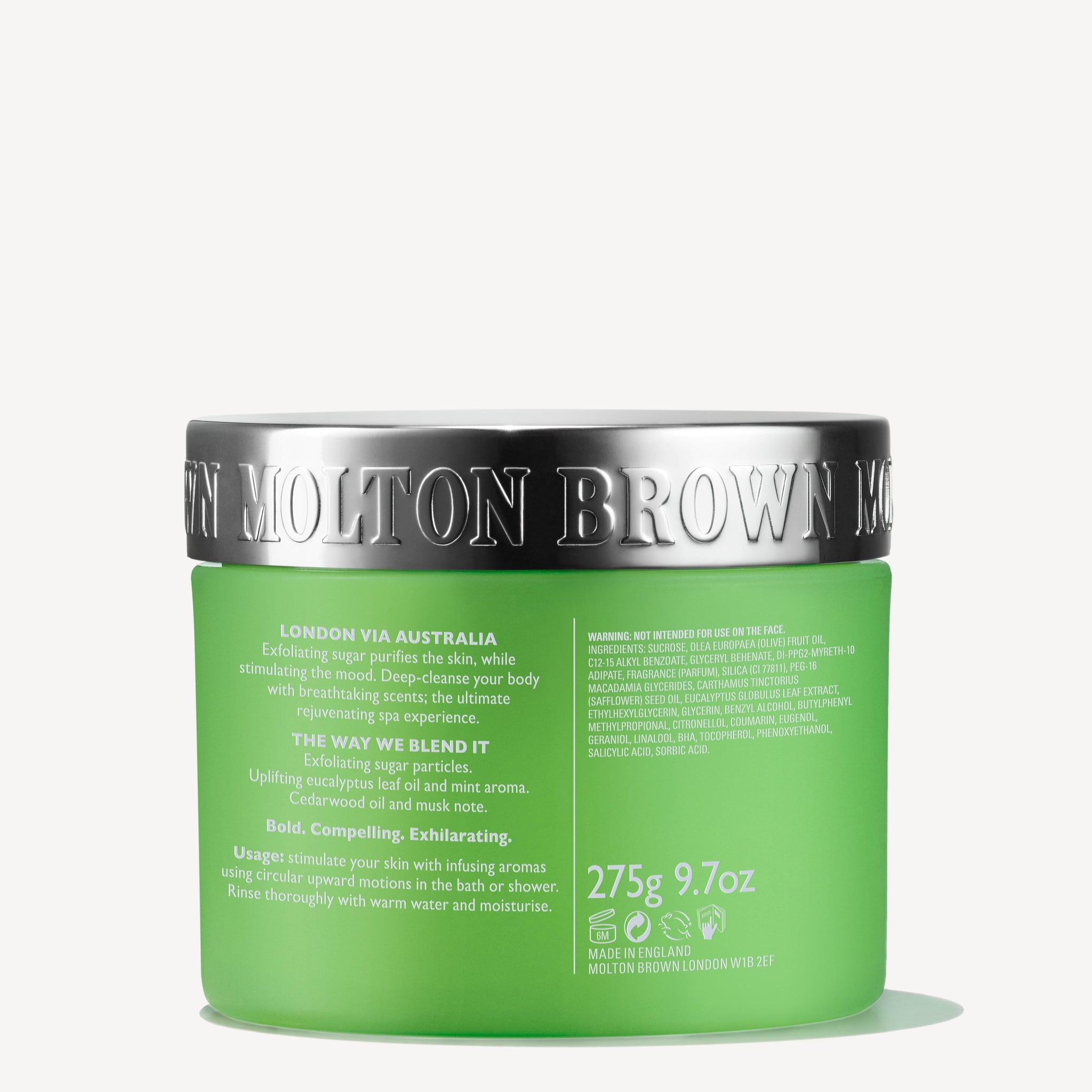 A green jar of Molton Brown Cyprus Infusing Eucalyptus Stimulating Body Polisher with a silver lid. The label mentions London via Australia, highlighting uplifting fragrances with aromas of limes and cedrat. The text also details usage instructions and a weight of 275g, promising to purify and smooth the skin.