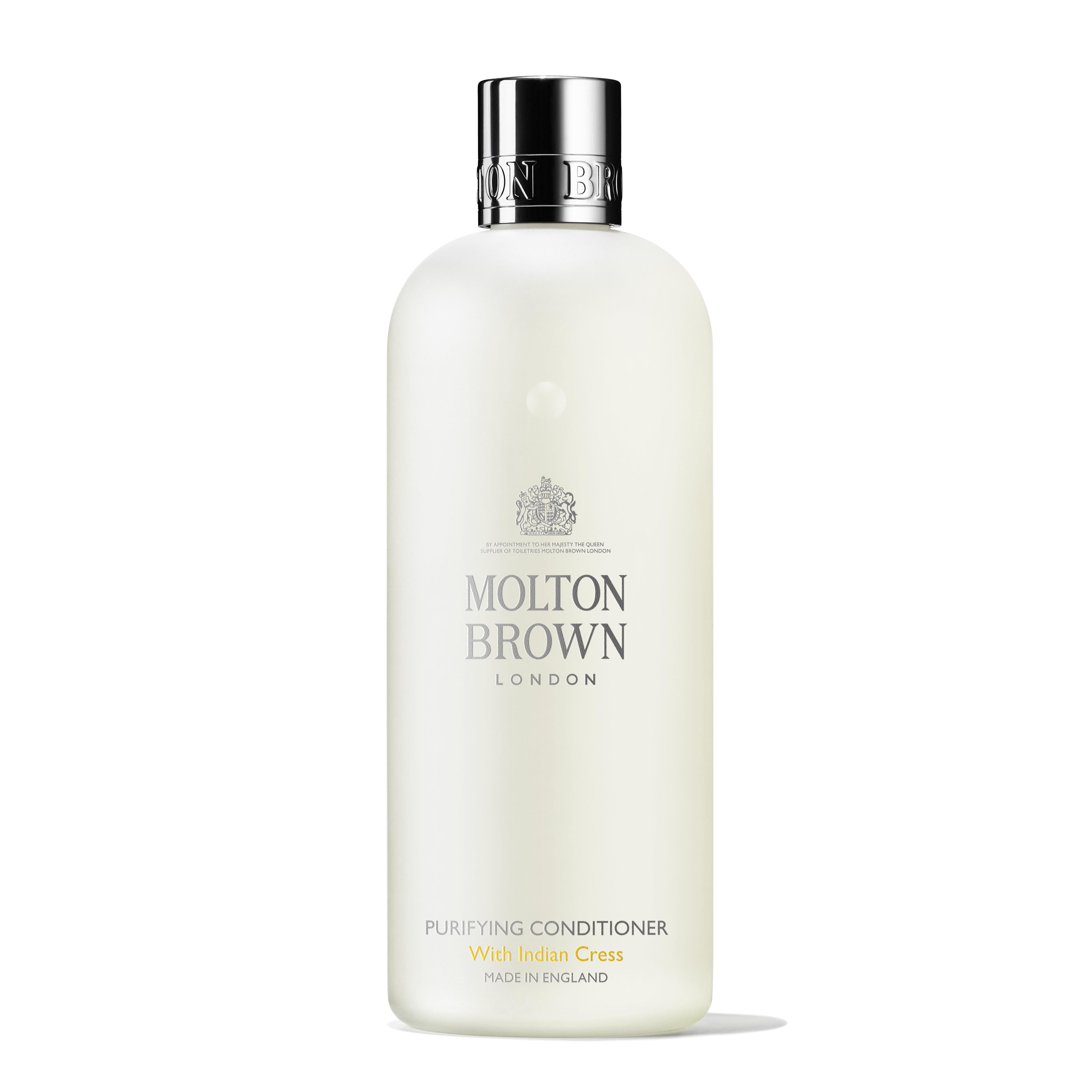 A white bottle of Molton Brown Cyprus Purifying Conditioner With Indian Cress 300ml is displayed. The text on the bottle features LONDON and Made in England in elegant fonts, with a simple, sleek design that exudes sophistication and is enhanced by subtle notes of honeysuckle.