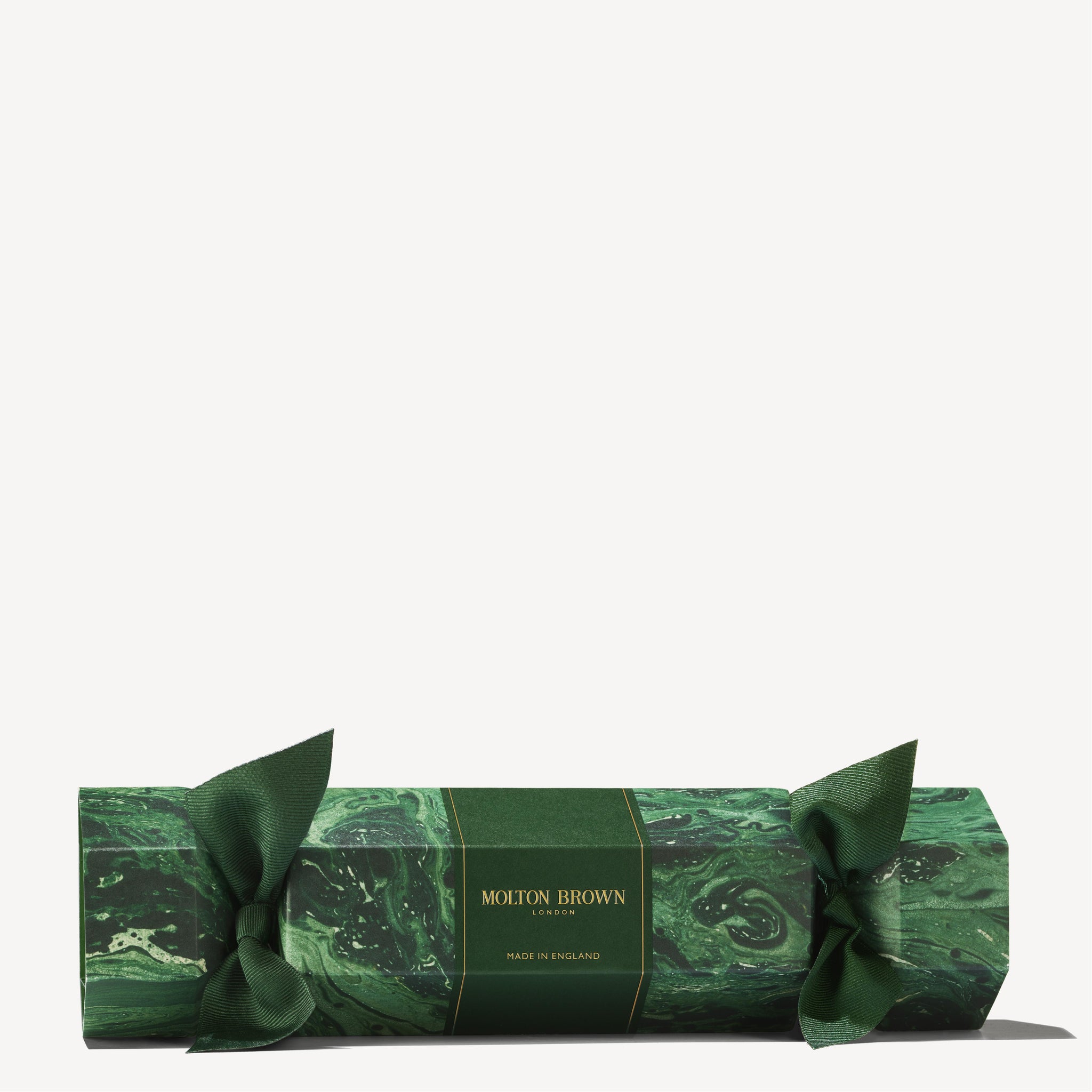 A festive green, marble-patterned MoltonBrown Cyprus Woody & Aromatic Christmas Cracker with ribbon ties on each end offers a sophisticated touch to your holiday gifting. Featuring Made in England branding at the center, it contains woody and aromatic body washes for an indulgently luxurious experience.