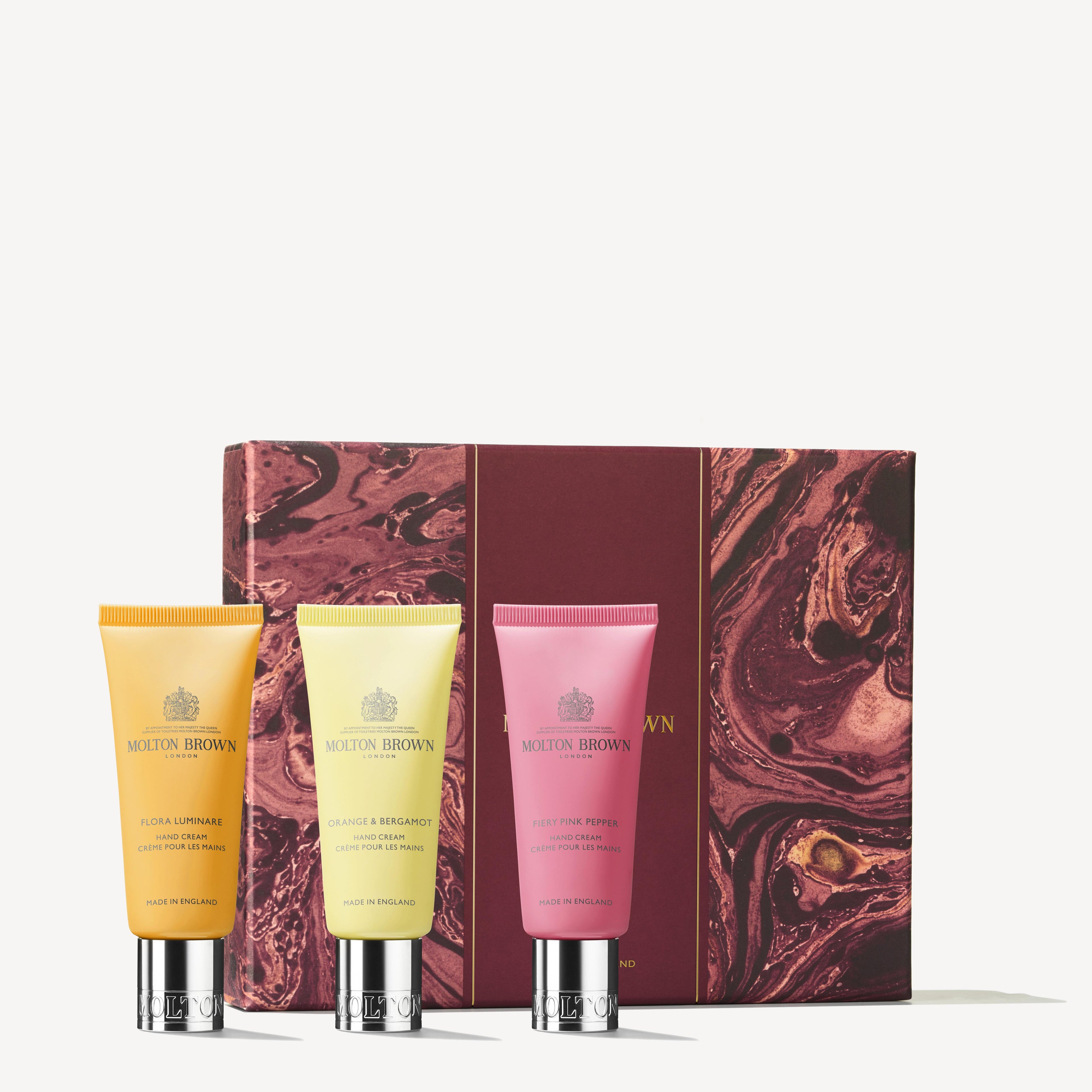 Introducing the Floral & Spicy Hand Care Gift Set by MoltonBrown Cyprus, showcasing three luxurious hand creams enriched with shea butter. The set includes yellow, cream, and pink tubes, each exuding a delightful floral fragrance. The gift set is elegantly presented in front of a maroon and gold marbled design box.