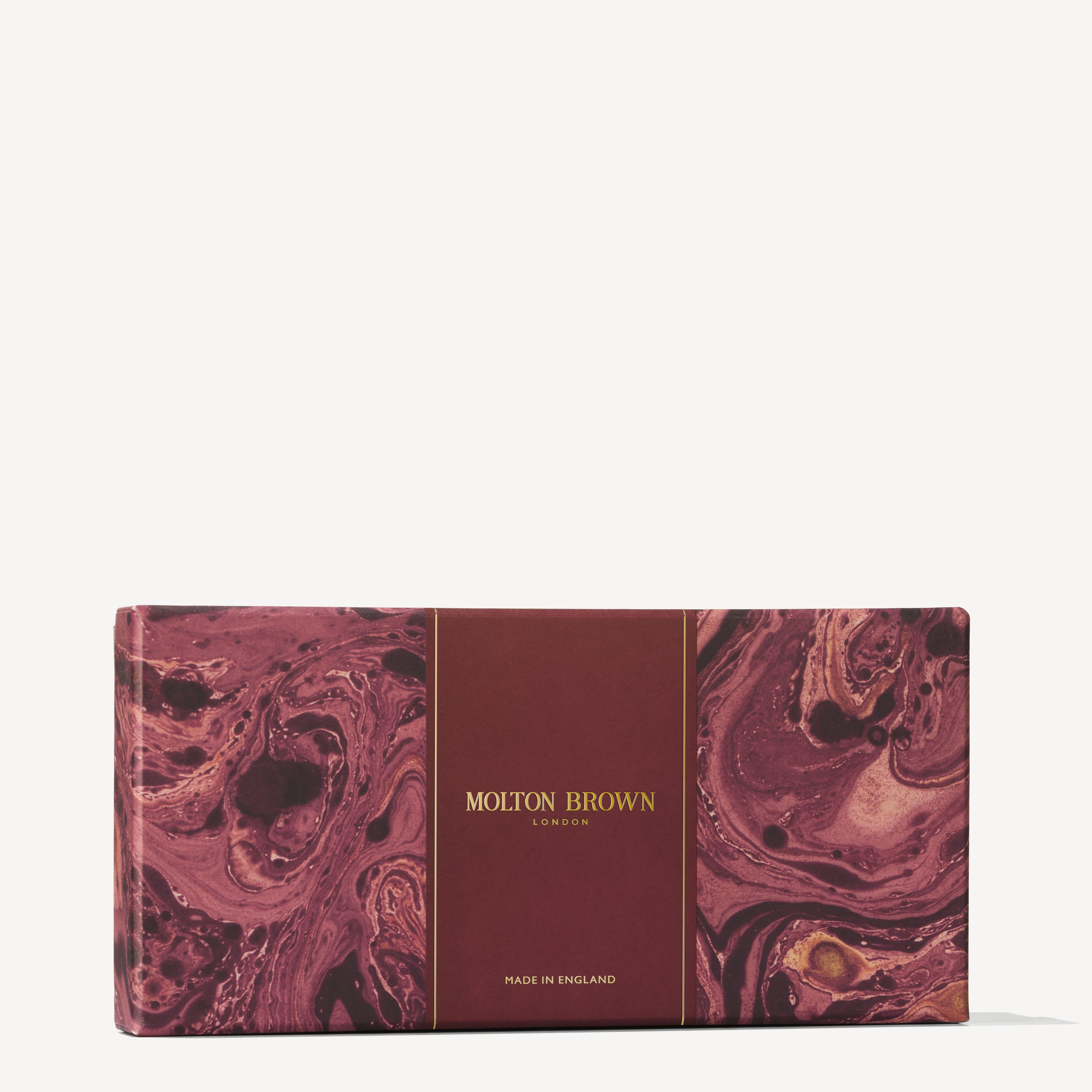 A rectangular box adorned with a marbled red and pink pattern and gold lettering subtly suggests the aromatic delights inside. The text features MoltonBrown Cyprus prominently in the center, with Made in England at the bottom, introducing their fruity, woody scented Festive Bauble Gift Set of shower gels.