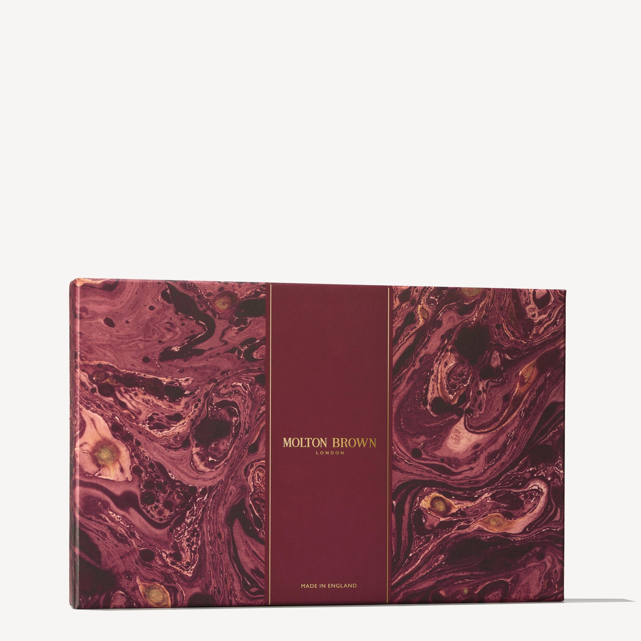 A maroon and gold marbled Stocking Filler Gift Set from MoltonBrown Cyprus, showcasing the brand's signature elegance, features swirls resembling polished stone. At its center, "MoltonBrown Cyprus" stands proudly, hinting at the luxurious body washes and exquisite fragrance concentrations awaiting inside.