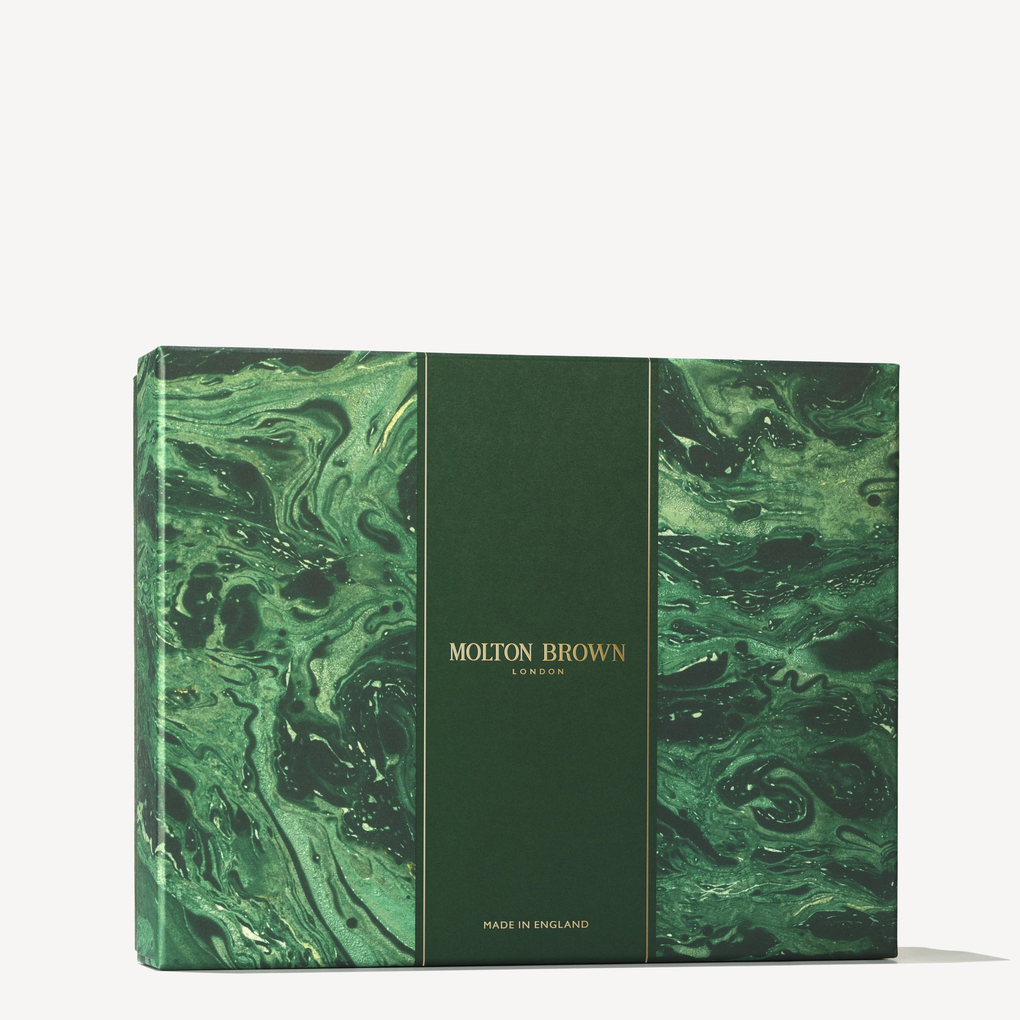 A gift box from MoltonBrown Cyprus, featuring a green marble-like swirl pattern and gold text, radiates the charm of the Woody & Aromatic Body Care Gift Set. It displays "Molton Brown London" and "Made in England," making it perfect for indulging in a restorative body wash ritual.