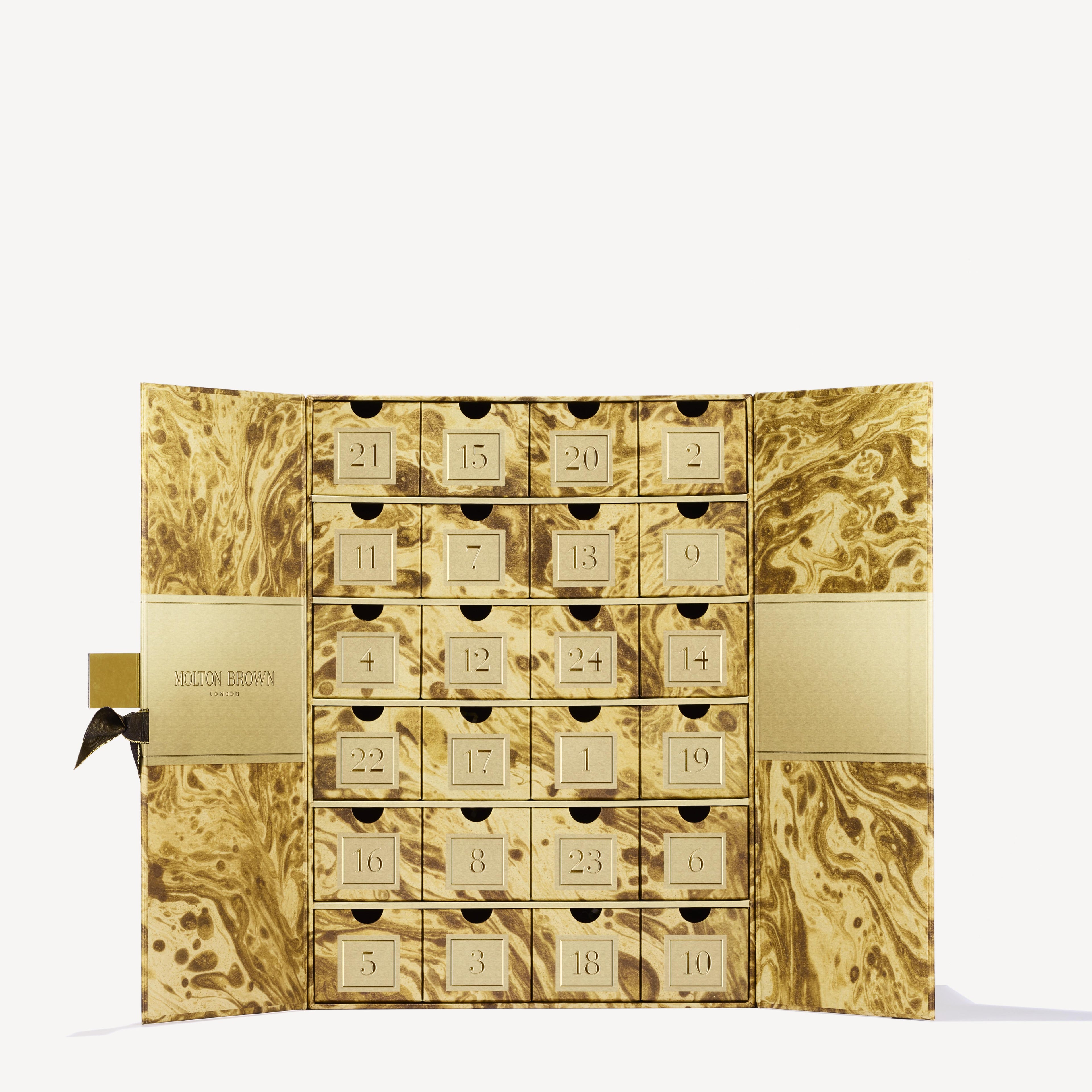 Introducing the MoltonBrown Cyprus Advent Calendar, a limited edition treasure presented in an exquisite gold and brown marbled box, reminiscent of masterful marble artistry. This calendar boasts 24 numbered drawers, each concealing delightful fragrant surprises. The subtle placement of the Molton Brown logo on the left side completes its elegant design.