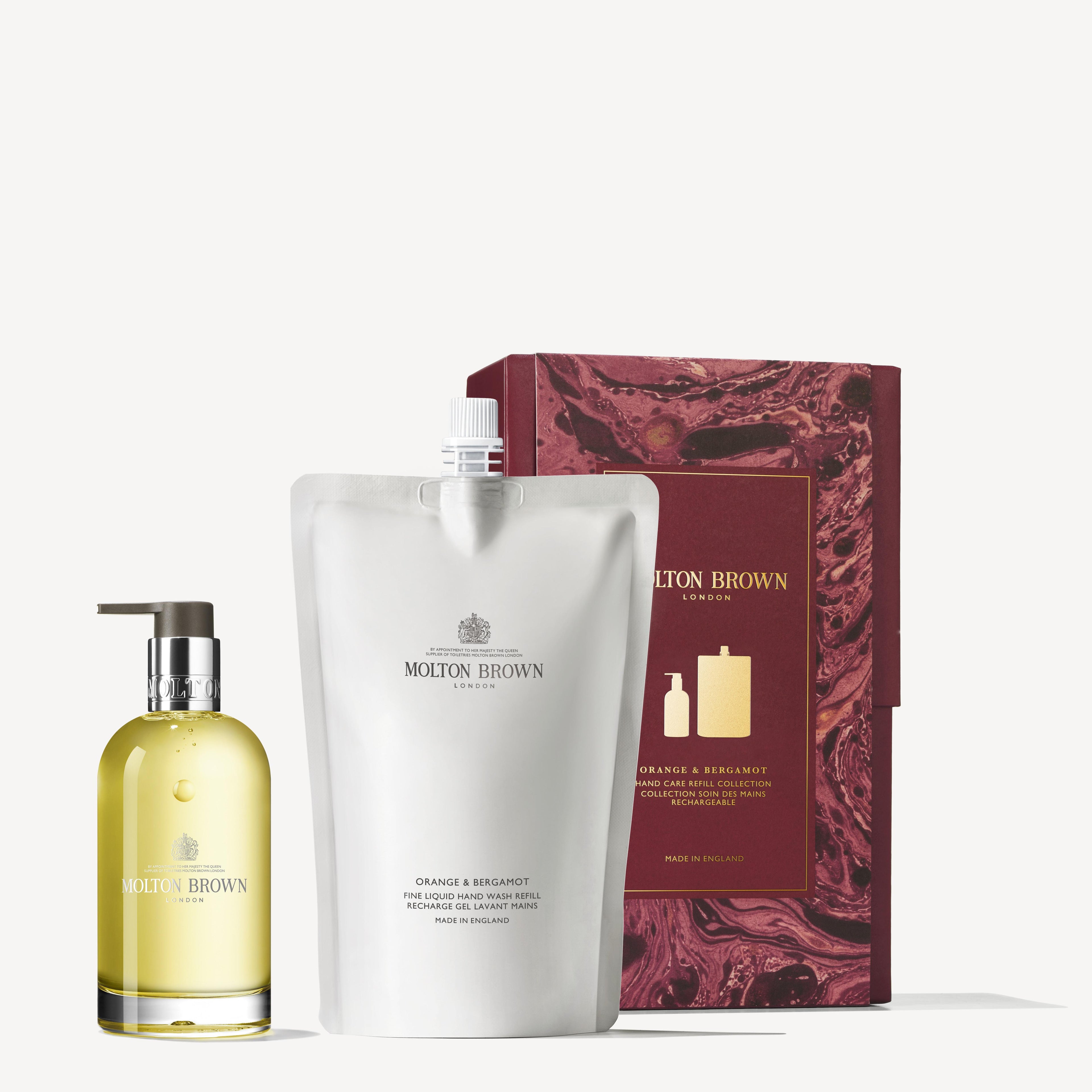 The MoltonBrown Cyprus Orange & Bergamot Hand Care Refill Gift Set includes a clear refillable dispenser bottle and a white pouch, all exuding a refreshing citrus aroma. It is elegantly displayed next to a maroon and gold patterned box, with the brand logo and product details clearly visible.