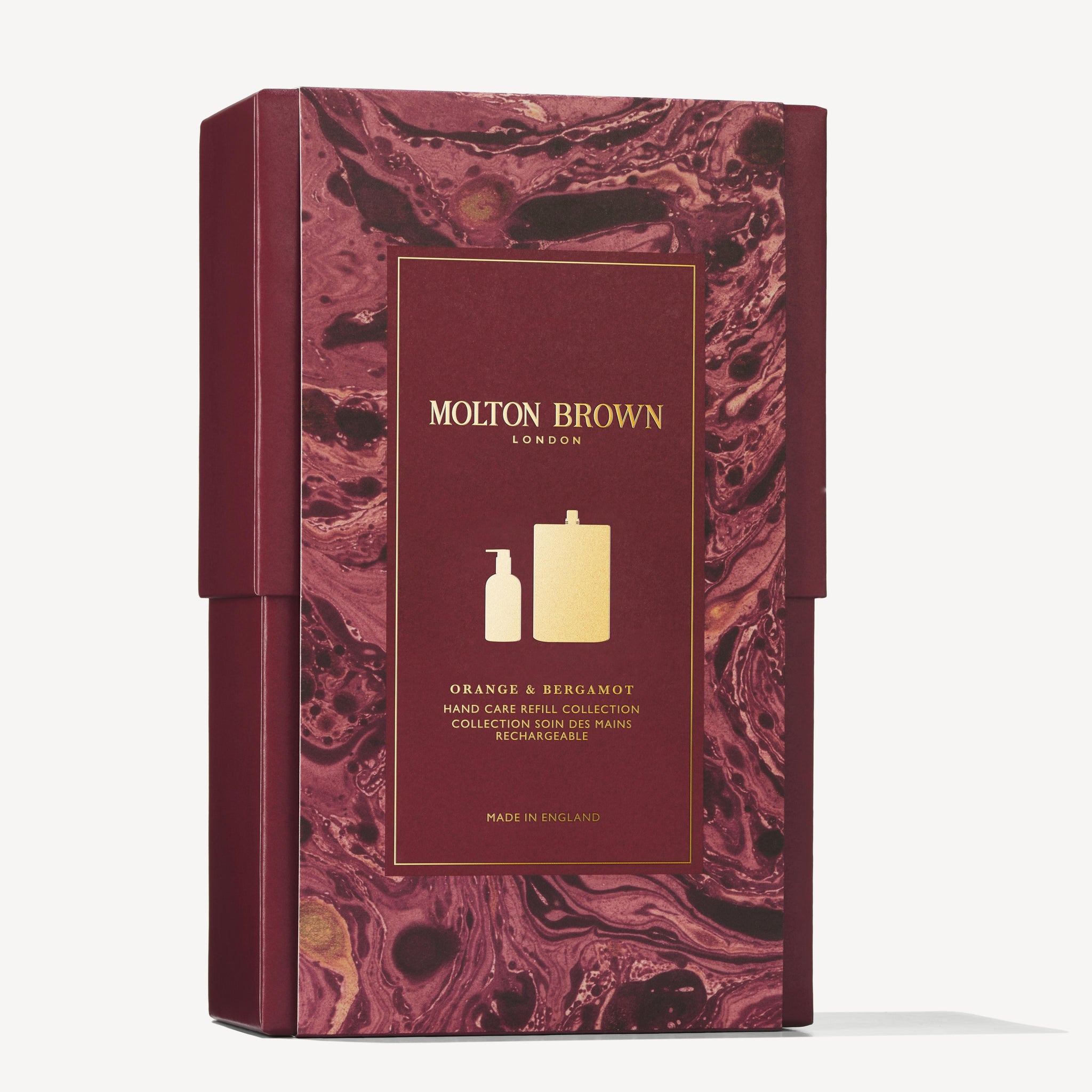 A maroon and gold MoltonBrown Cyprus gift box highlights the refillable Orange & Bergamot Hand Care Refill Gift Set. The box features images of a soap dispenser and citrus-scented refill against a marbled background, with the text proudly stating "Made in England.