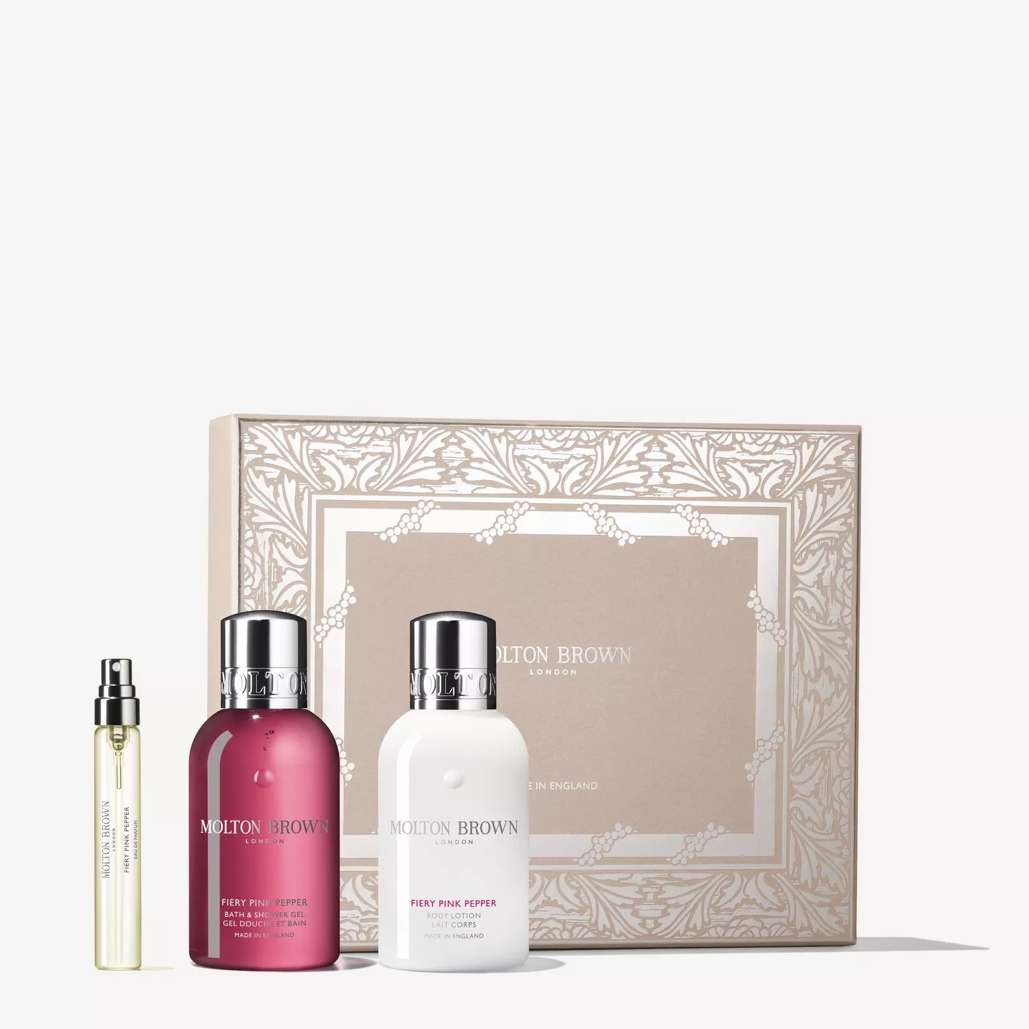 The MoltonBrown Cyprus Fiery Pink Pepper Travel Gift Set includes a beige gift box, pink pepper shower gel, white lotion, and a travel-size fragrance in a clear spray vial arranged together.
