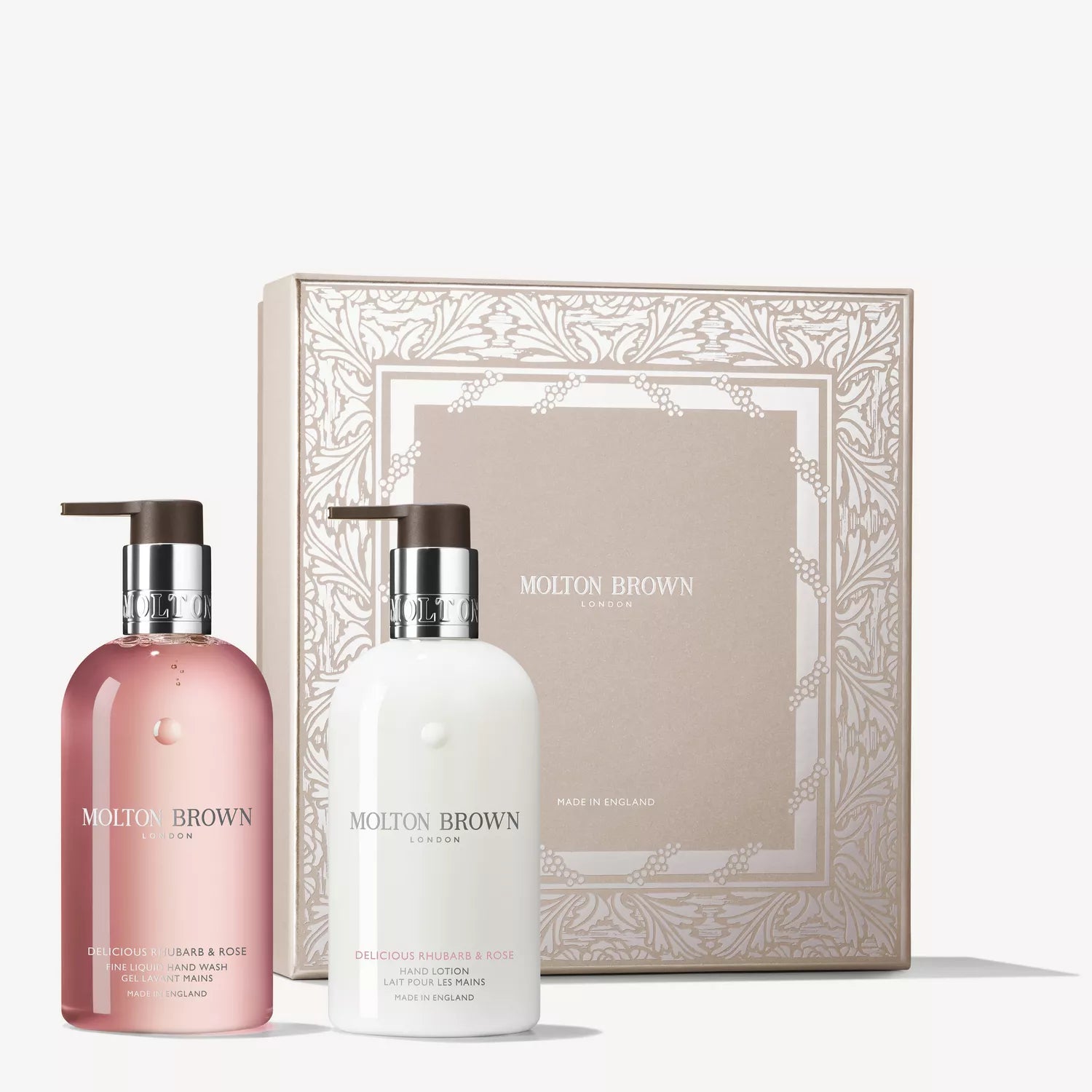 The MoltonBrown Cyprus Delicious Rhubarb & Rose Hand Care Collection features two pump bottles in pink and white, presented before a decorative beige and white box with floral details and the Molton Brown logo.
