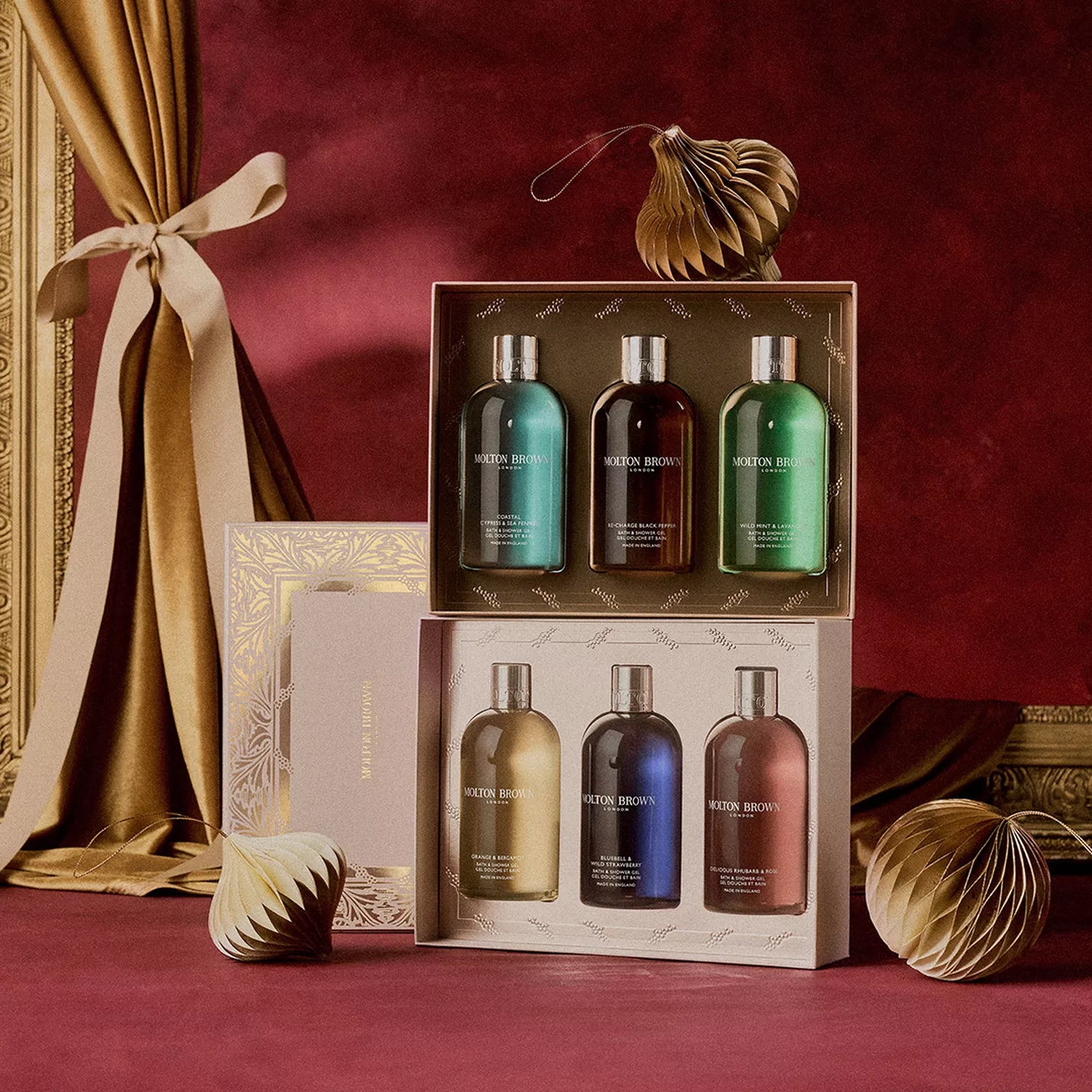 The MoltonBrown Cyprus Floral & Fruity Body Care Gift Set features six vibrant bath gels, beautifully arranged in two gold-trimmed boxes with festive decorations, perfect for a luxurious and colorful gift.