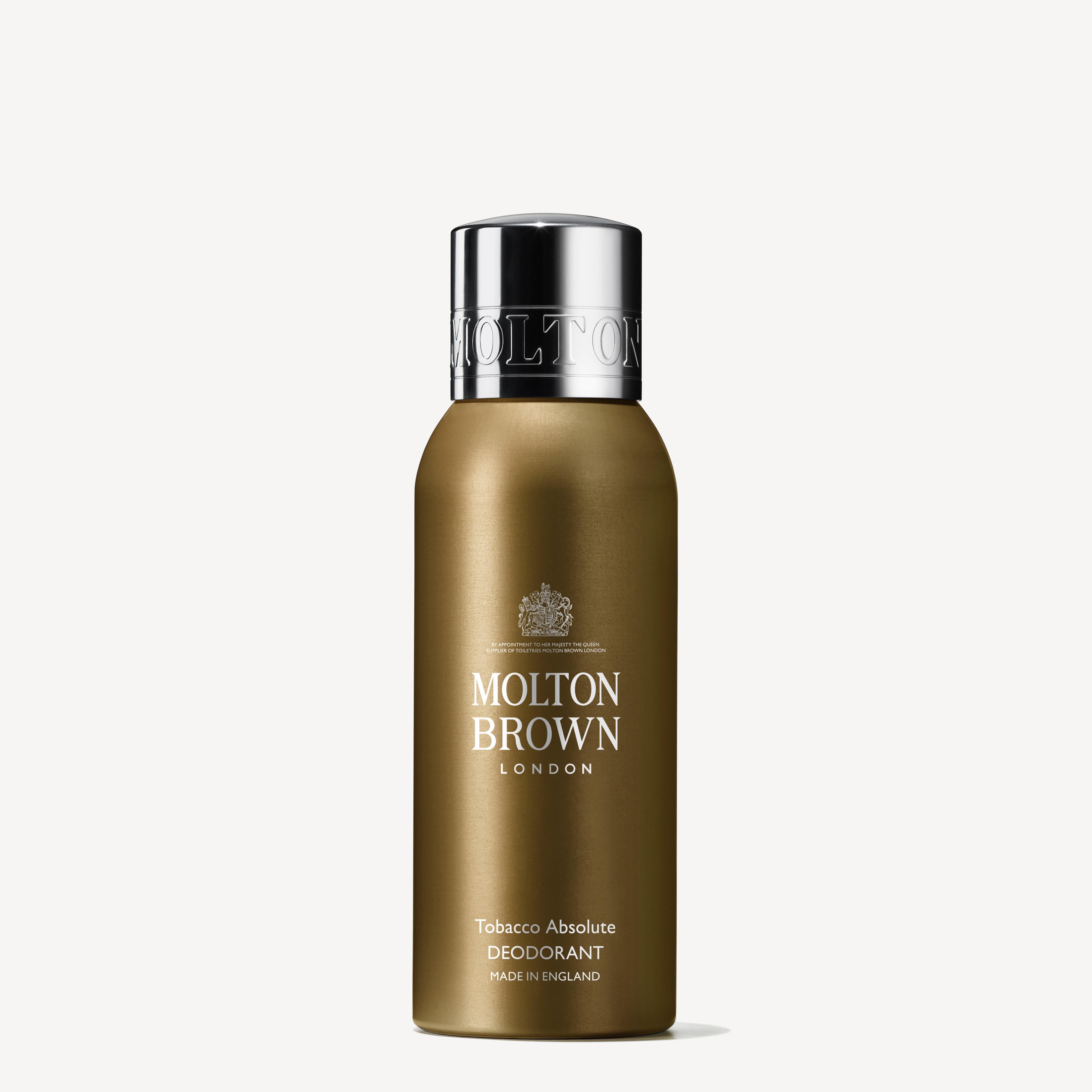 A bronze metallic bottle of Tobacco Absolute Deodorant by Molton Brown Cyprus exudes a refreshing grapefruit hint. The design features a sleek silver cap and prominently displays 'Molton Brown London' and 'Made in England' on a plain white background.