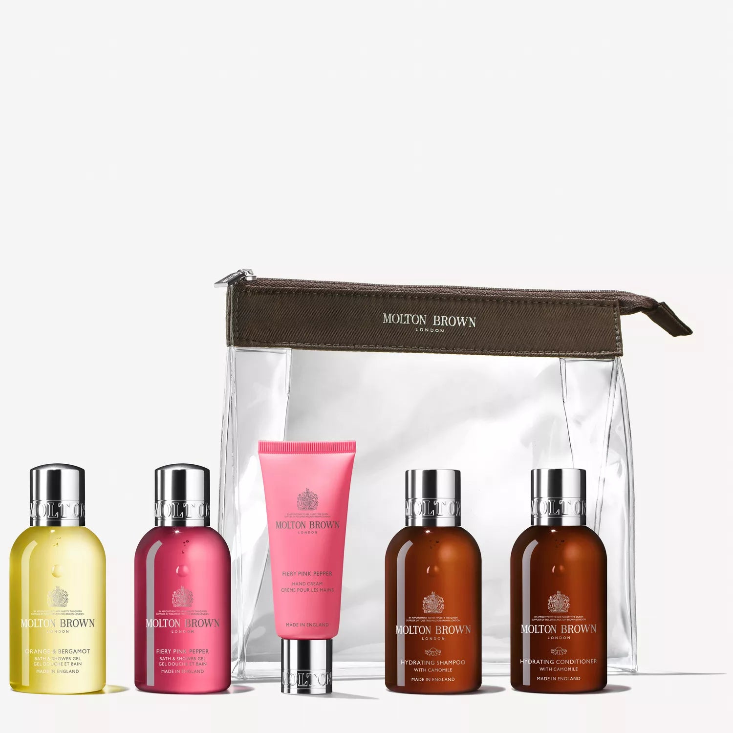 The Revived Voyager Body & Hair Carry-On Bag by Molton Brown Cyprus includes five travel-size bottles: two brown (shampoo and conditioner), one light pink (shower gel), one dark pink (body lotion), and one yellow (body wash) for a luxurious, hydrating experience wherever you go.