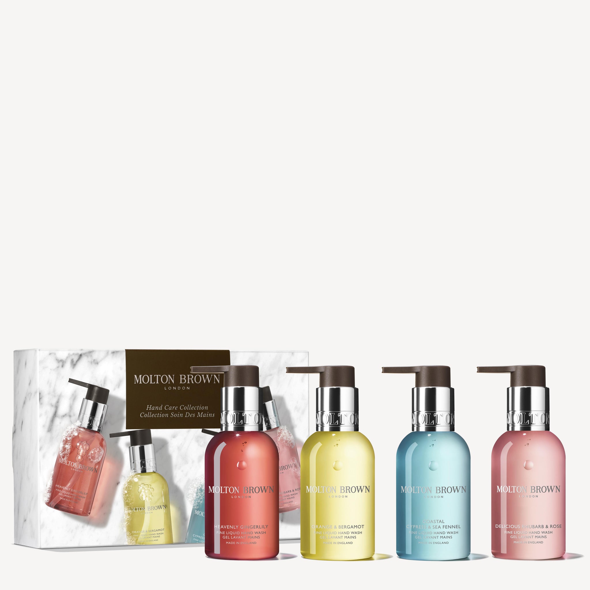 A set of four Fresh & Floral Hand Care Collection hand washes by Molton Brown Cyprus, with elegant pump dispensers. The colorful bottles are arranged in front of a matching branded box, each exuding fruity-floral fragrances.