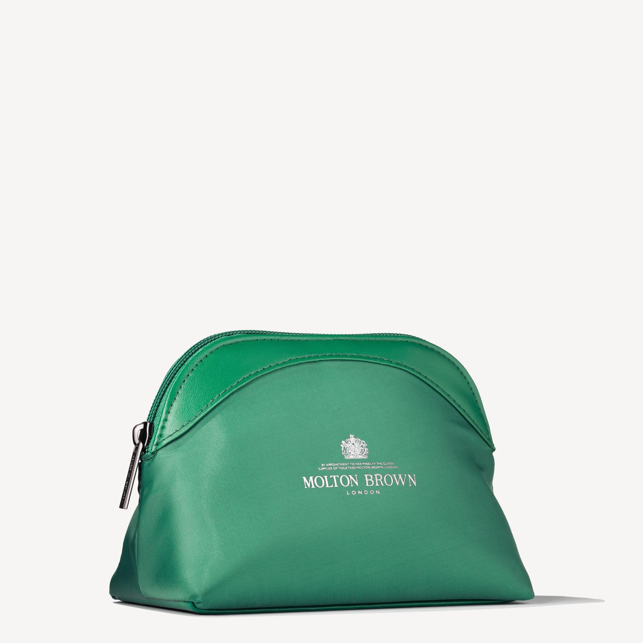 Introducing the Elegant Escapist Body & Hair Mini Travel Bag from Molton Brown Cyprus, a striking green travel pouch with a silver zipper perfect for your bath and body care essentials. This pouch is adorned with the brand's logo in white and features an elegant crown graphic. It has a gently curved top and is set against a simple, light background.