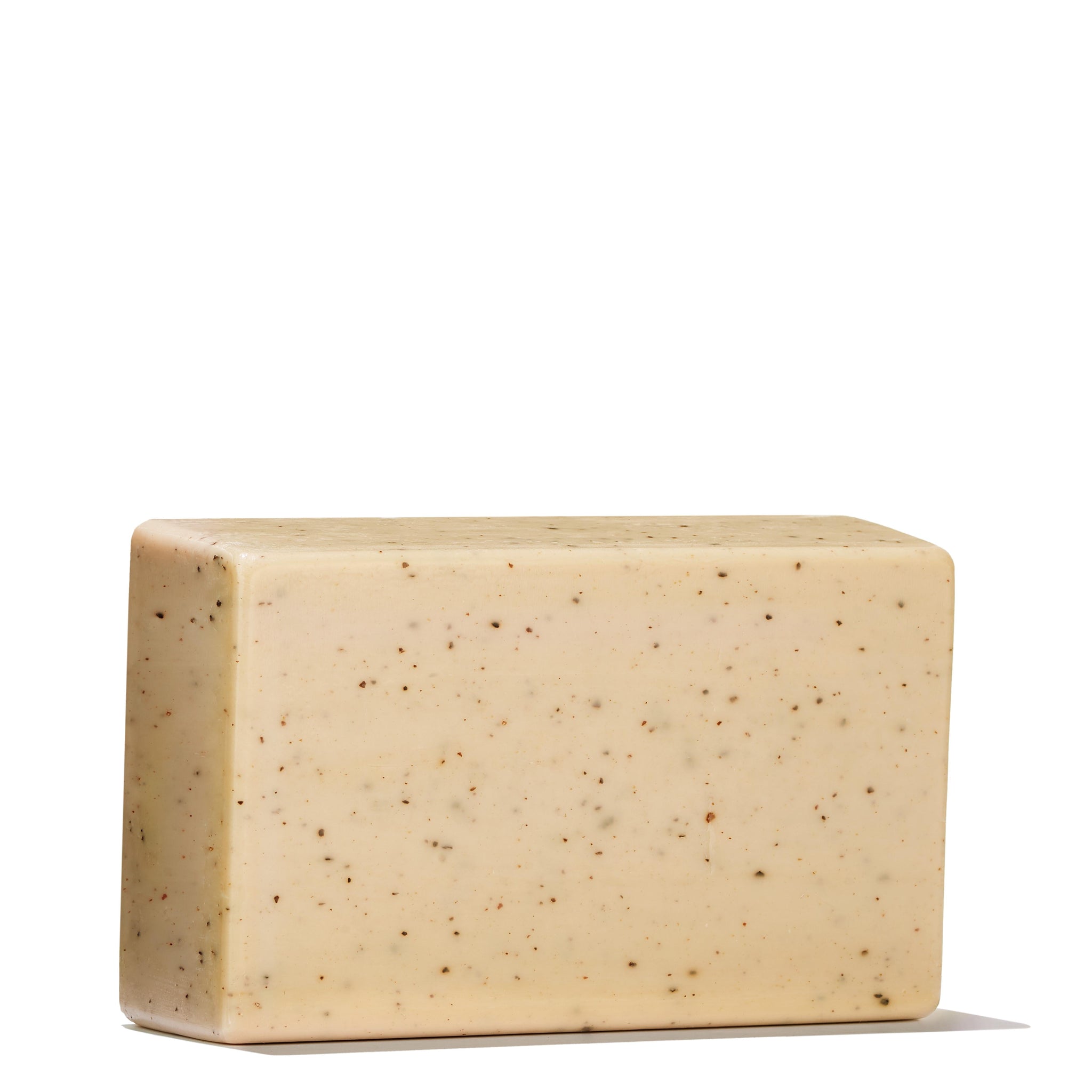 The Re-charge Black Pepper Bodyscrub Bar 250g from MoltonBrown Cyprus is presented against a white backdrop. This rectangular beige bar, speckled with small dark flecks, highlights the invigorating essence of Madagascan black peppercorn oil, with a subtle shadow cast beneath it.