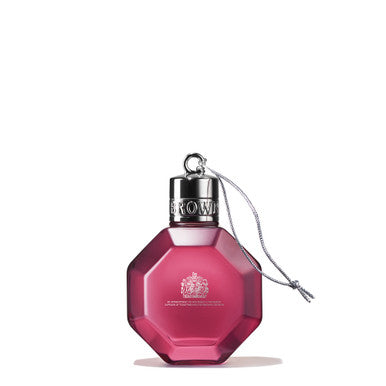 The Fiery Pink Pepper Festive Bauble by MoltonBrown Cyprus, designed in a pink octagonal shape reminiscent of a festive bauble, draws attention with its silver cap and attached cord. The cap is engraved with the word "CROWN," while the bottle showcases MoltonBrown's logo and text near the bottom. Set against a simple white background, this elegant 75ml perfume bottle stands out beautifully.