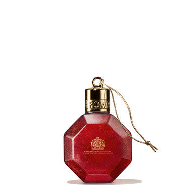 The MoltonBrown Cyprus Merry Berries & Mimosa Festive Bauble is a red, octagonal perfume bottle designed to resemble a Christmas bauble. It has a gold cap and a thin gold string attached, featuring an embossed emblem near the top. This floral-fruity creation elegantly stands against a plain white background.