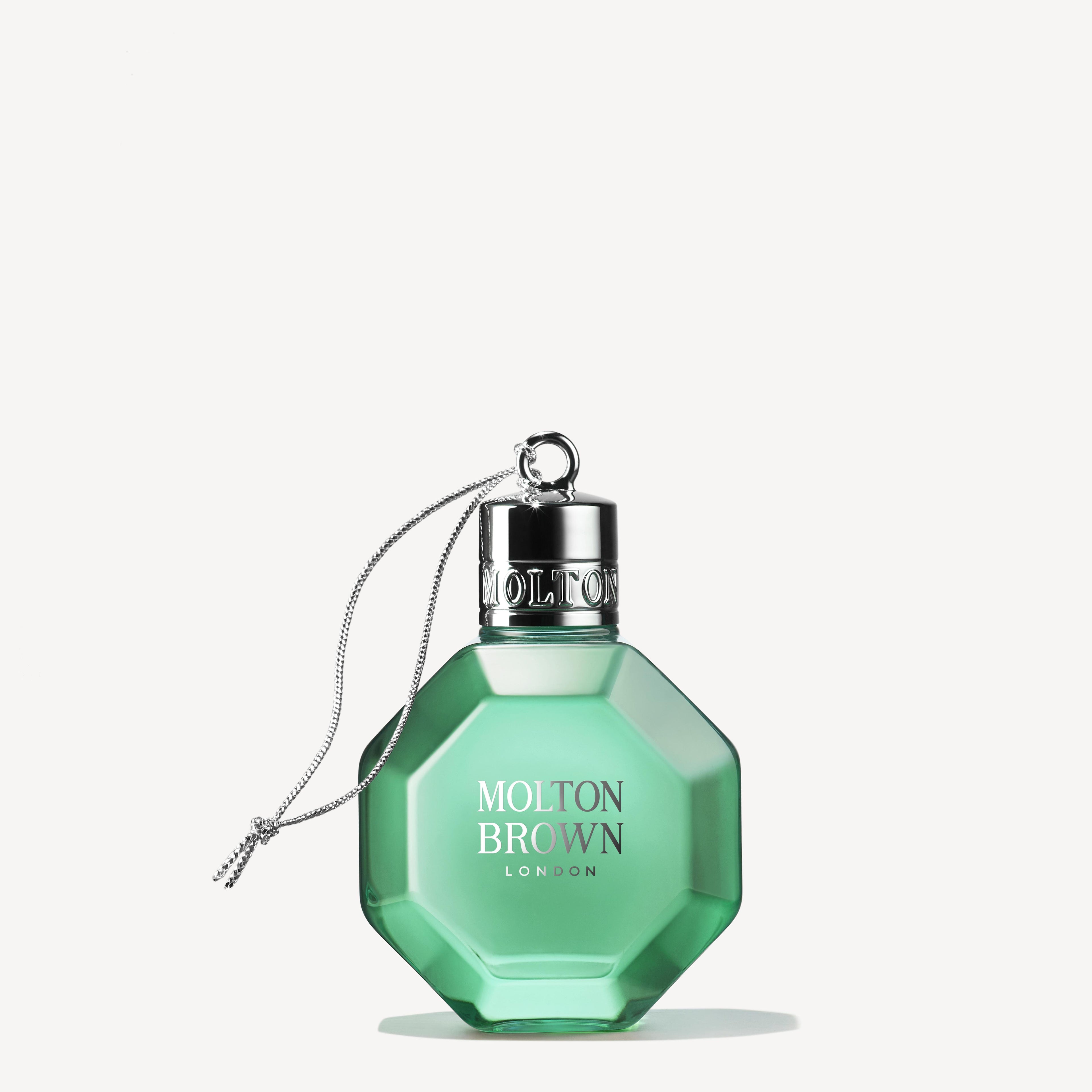 A green, octagonal perfume bottle with a silver cap and pull-cord releases a wild mint and lavandin scent. The label reads MoltonBrown Cyprus. The bottle is displayed against a plain, light background.