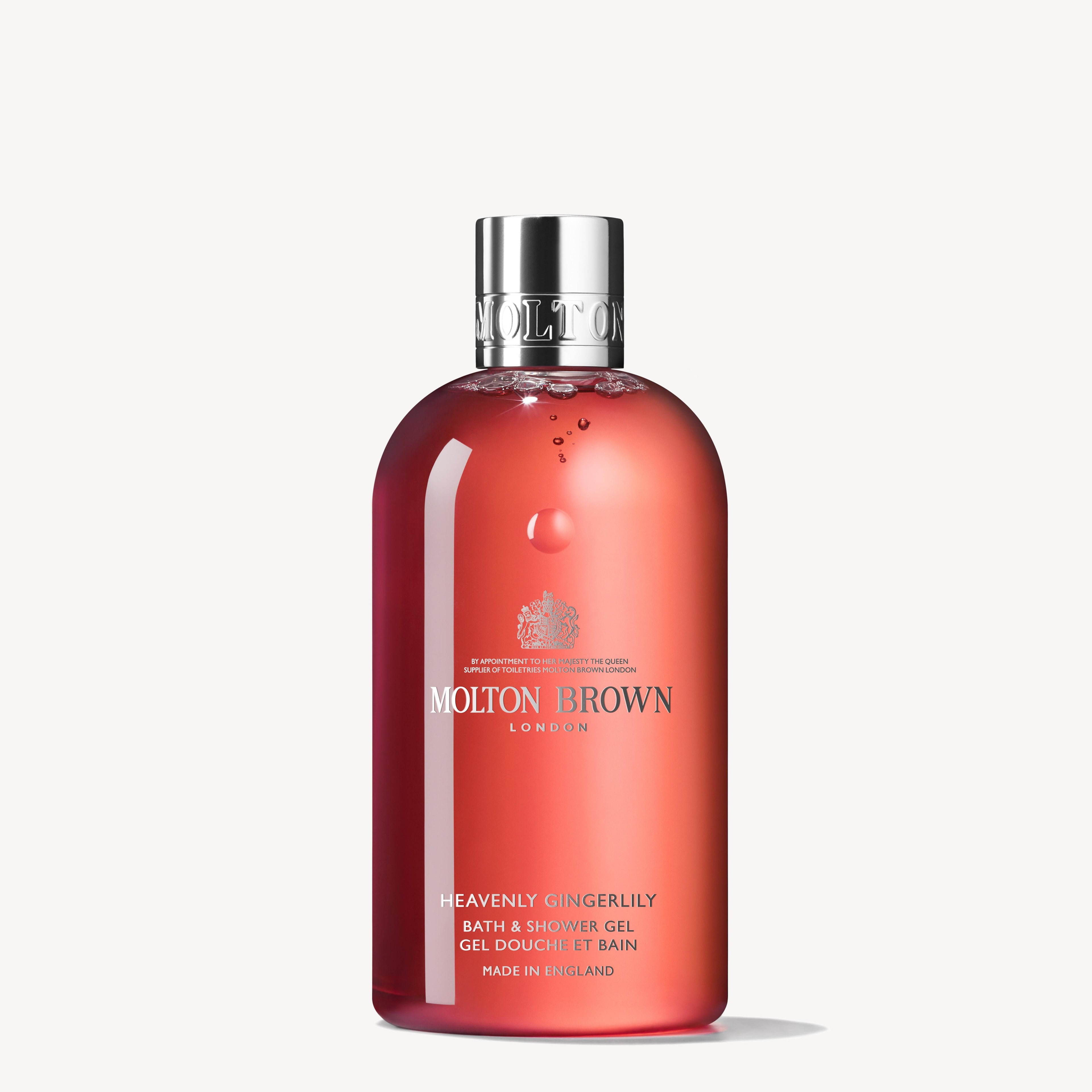 The Heavenly Gingerlily Bath & Shower Gel 300ml by MoltonBrown Cyprus captures the essence of exotic beaches. Encased in a red bottle with a silver cap, it proudly showcases the brand name and product details in crisp white lettering.