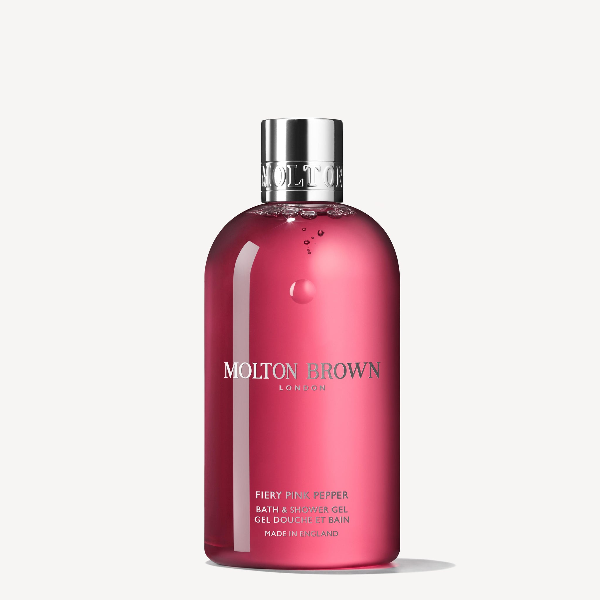 The Fiery Pink Pepper Bath & Shower Gel 300ml by MoltonBrown Cyprus is an invigorating body wash. It comes in a transparent red bottle that highlights notes of pink pepper and patchouli, with the brand name displayed in white text, topped off with a silver cap against a plain white background.