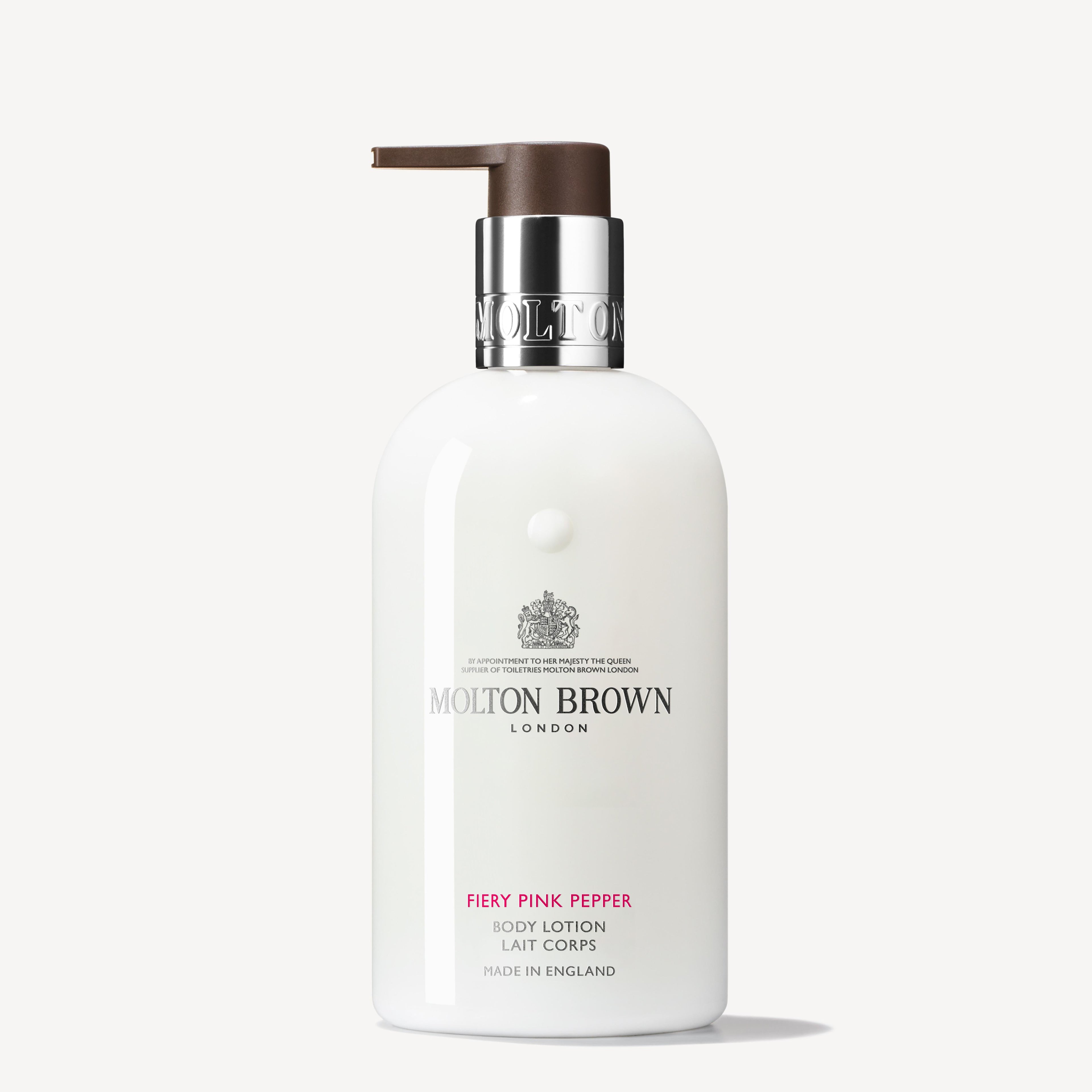 The Fiery Pink Pepper Body Lotion 300ml by MoltonBrown Cyprus exudes luxury with its white bottle and brown pump top. The label features silver and pink text that highlights the invigorating blend of spicy pink pepper and subtle hints of ginger.