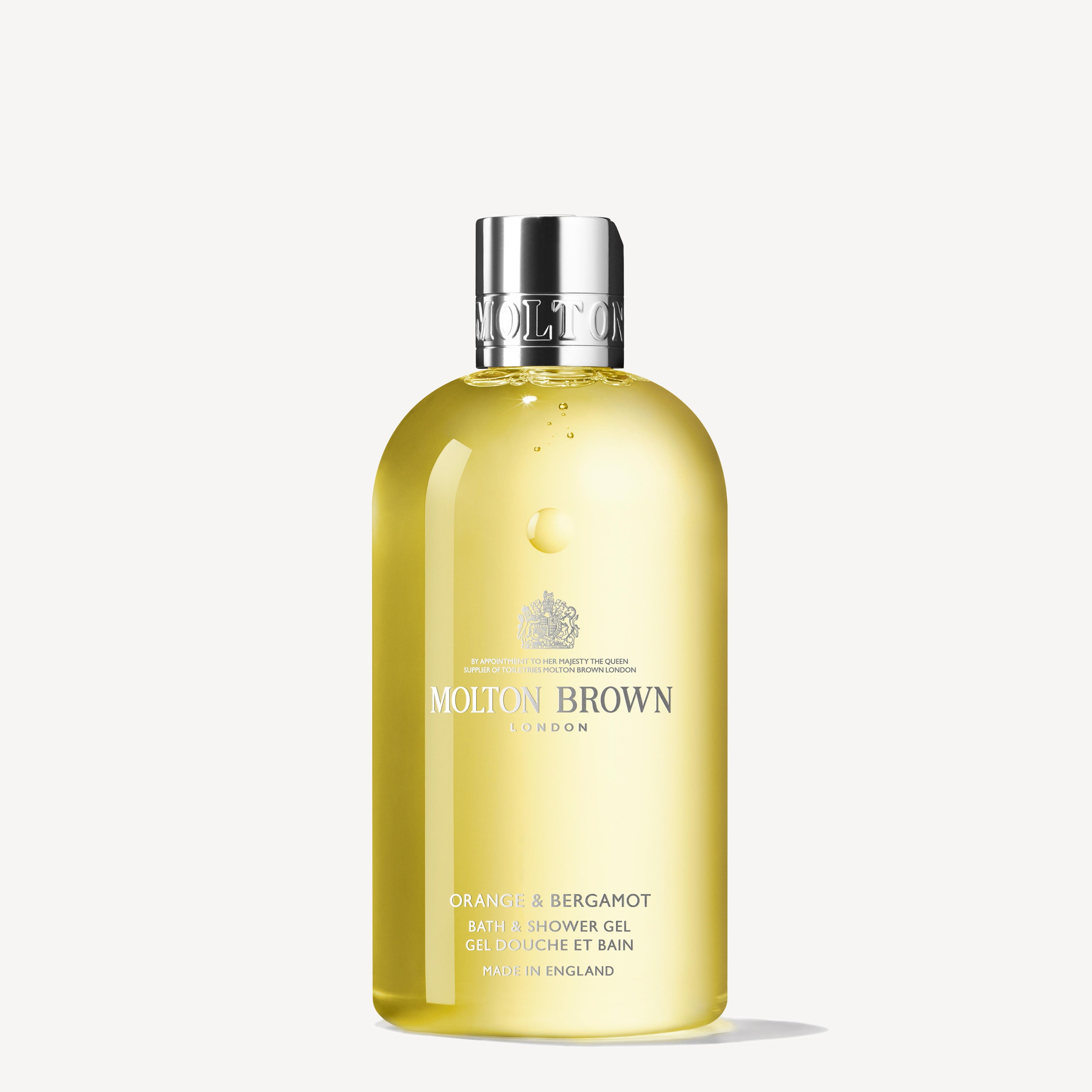 The Orange & Bergamot Bath & Shower Gel 300ml from MoltonBrown Cyprus comes in a transparent yellow bottle, exuding an invigorating fragrance. Accented by a silver cap and labeled with "London" and "Made in England," this Sevillian orange delight is beautifully displayed against a simple white background.