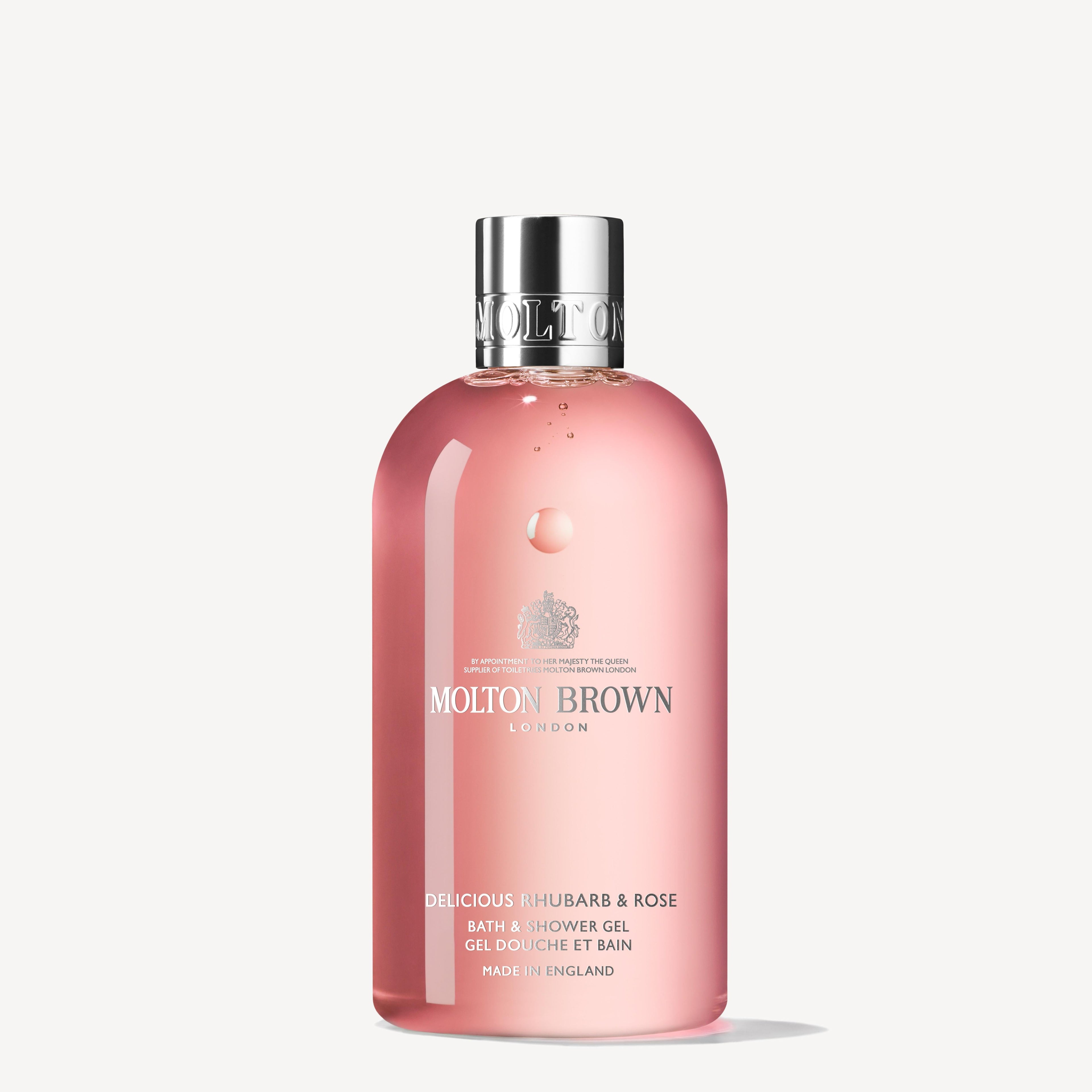 A 300ml pink bottle of MoltonBrown Cyprus' Delicious Rhubarb & Rose Bath & Shower Gel is highlighted by zesty grapefruit notes. It comes with a silver cap and has clear text on the front, set against a simple, light background.