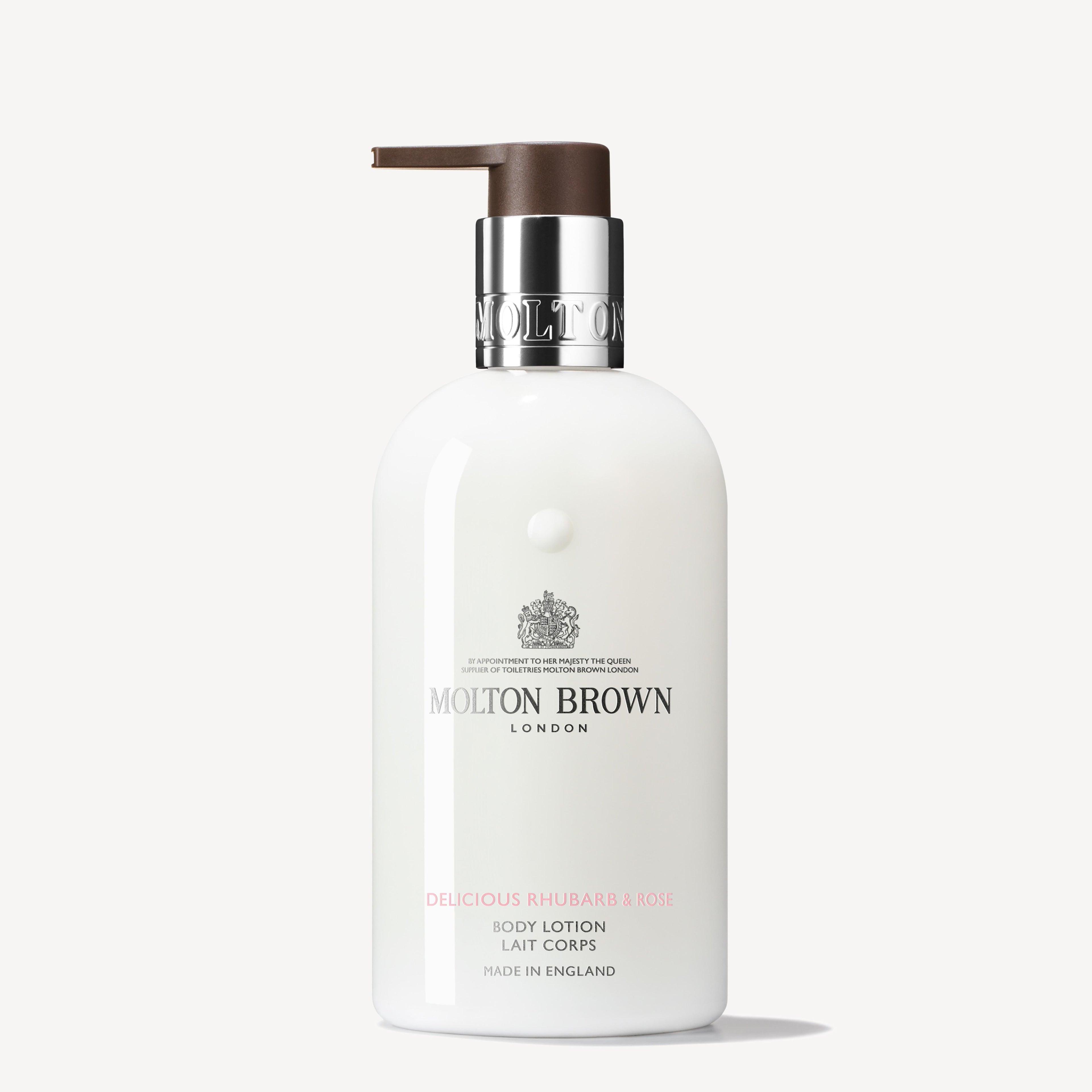 A 300ml bottle of MoltonBrown Cyprus Delicious Rhubarb & Rose Body Lotion with a pump dispenser offers an enchanting fragrance. The elegant white bottle adorned with silver and brown accents, labeled "Made in England," adds a luxurious touch to your skincare routine.