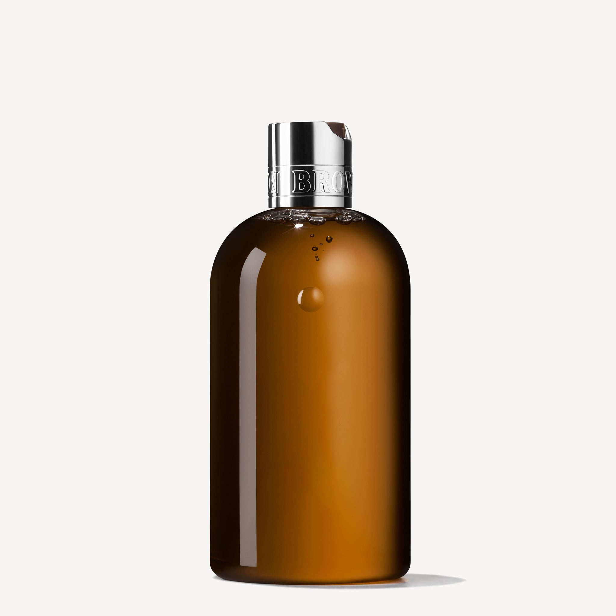 A 300ml bottle of MoltonBrown Cyprus Tobacco Absolute Bath & Shower Gel, featuring a sleek brown cylindrical design, stands elegantly with a metallic cap. The subtly reflective bottle against a plain light grey background exudes an aura of sophistication and warmth.