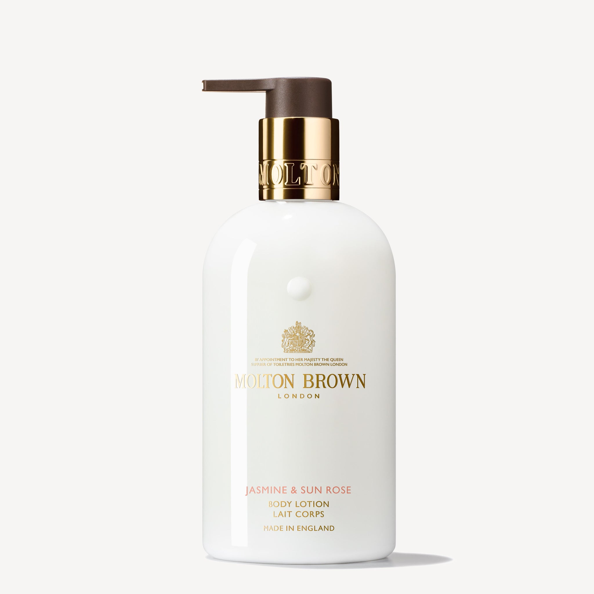 A white bottle of MoltonBrown Cyprus Jasmine & Sun Rose Body Lotion 300ml features a gold pump dispenser. The label displays the brand name in gold lettering with a crest logo above it. Text below describes the jasmine-infused body lotion made in England, offering an exquisite fragrance.